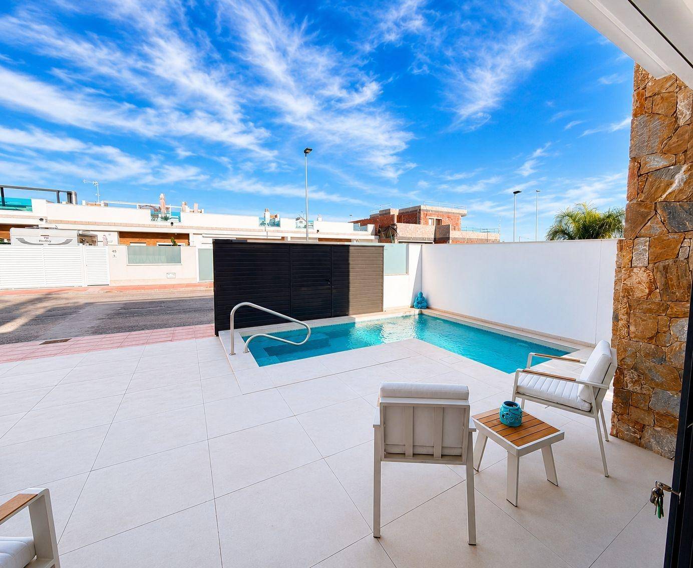 Sonniger Terrassenbereich mit kleinem Pool, bequemen Stühlen und Blick auf die Umgebung.