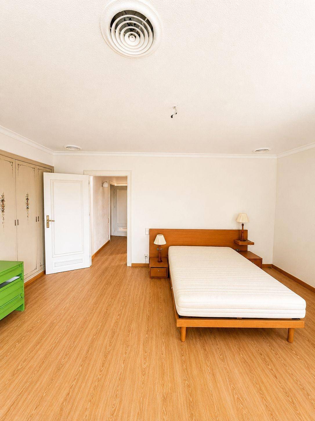 Helles Schlafzimmer mit Holzboden, einem Bettgestell und Einbauschränken, bereit zur individuellen Gestaltung.