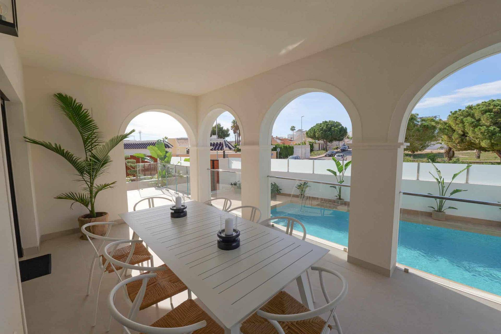 Geräumige überdachte Terrasse mit Essbereich und weitem Blick auf den Pool und die grüne Umgebung.