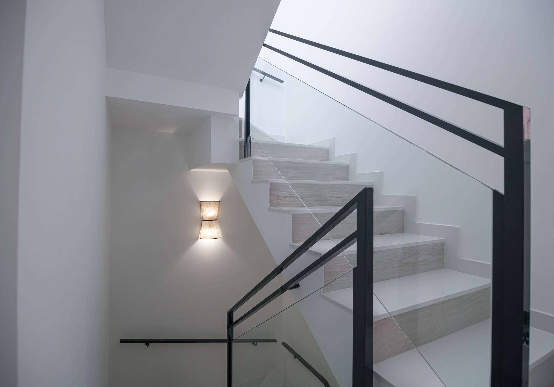 Moderne Treppe mit Glasgeländer und indirekter Beleuchtung, die die Etagen verbindet.