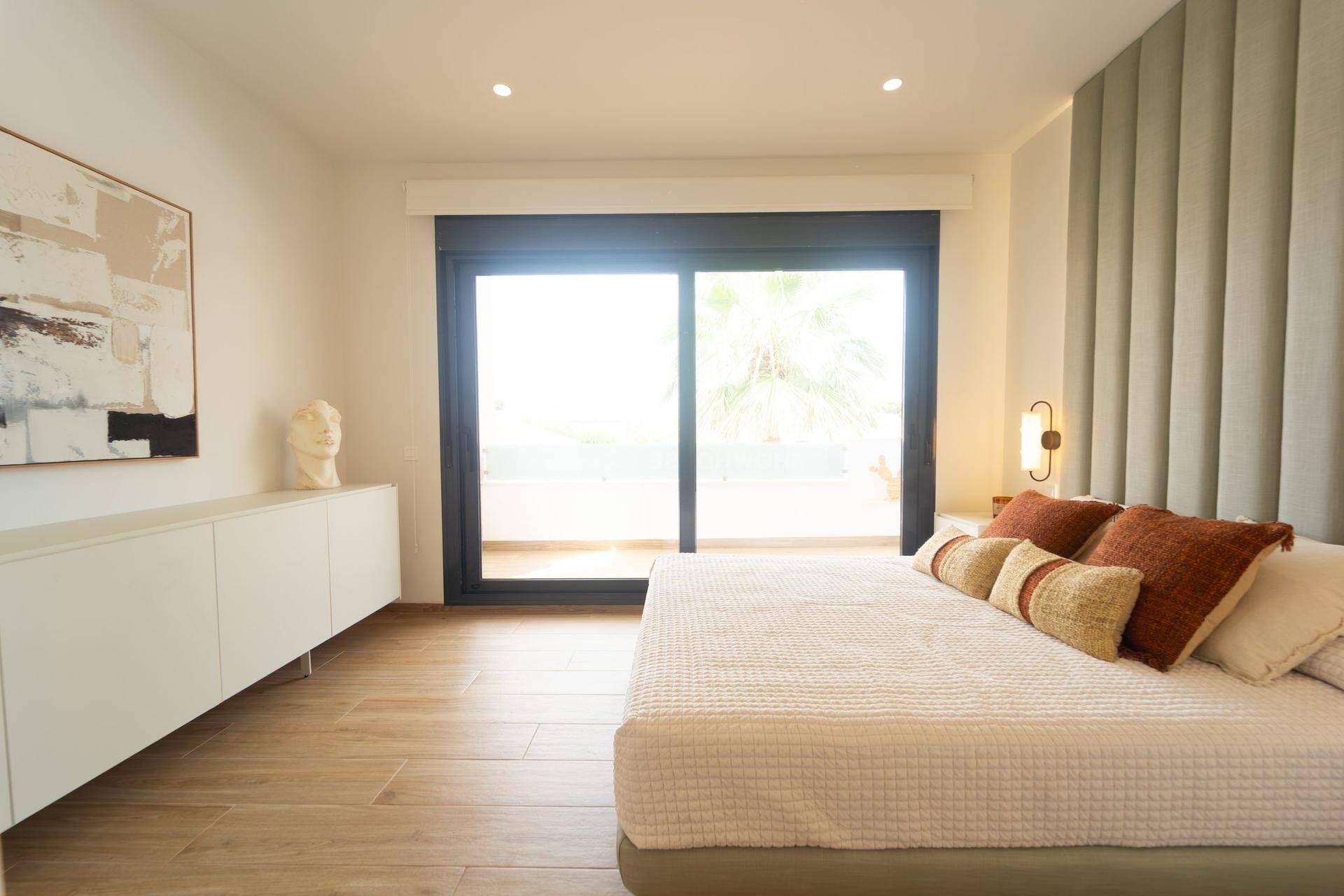 Geräumiges Schlafzimmer mit modernem Bett, schwebendem Sideboard und großen Fenstern.
