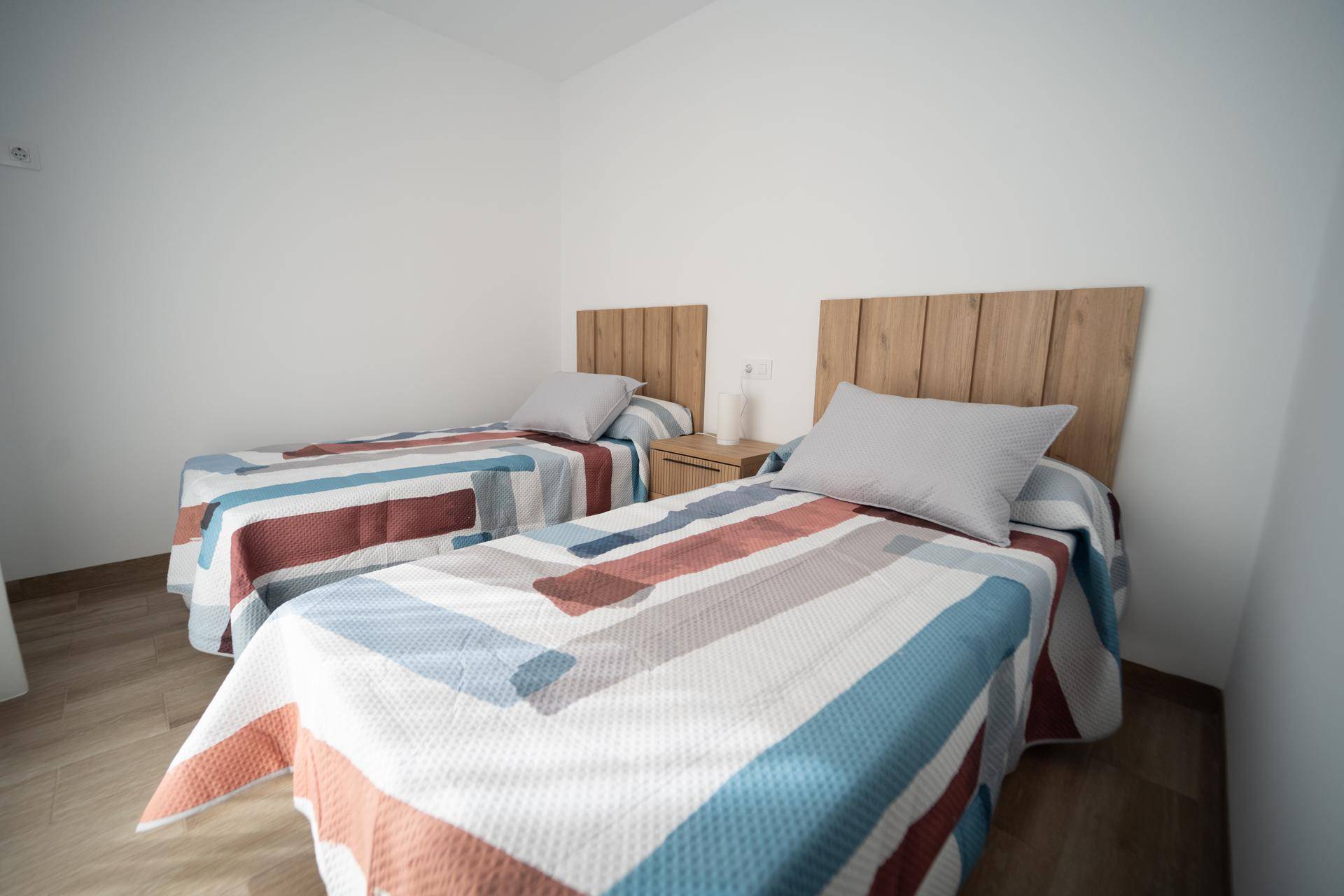 Gemütliches Schlafzimmer mit zwei Einzelbetten und Holzkopfteilen, hell und einladend.