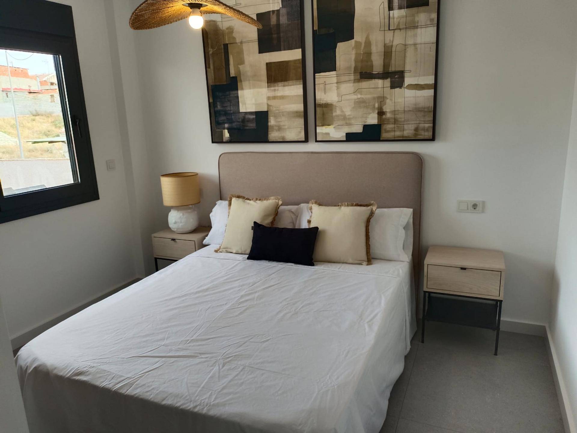 Helles Schlafzimmer mit Doppelbett, Nachttischen und großem Fenster.