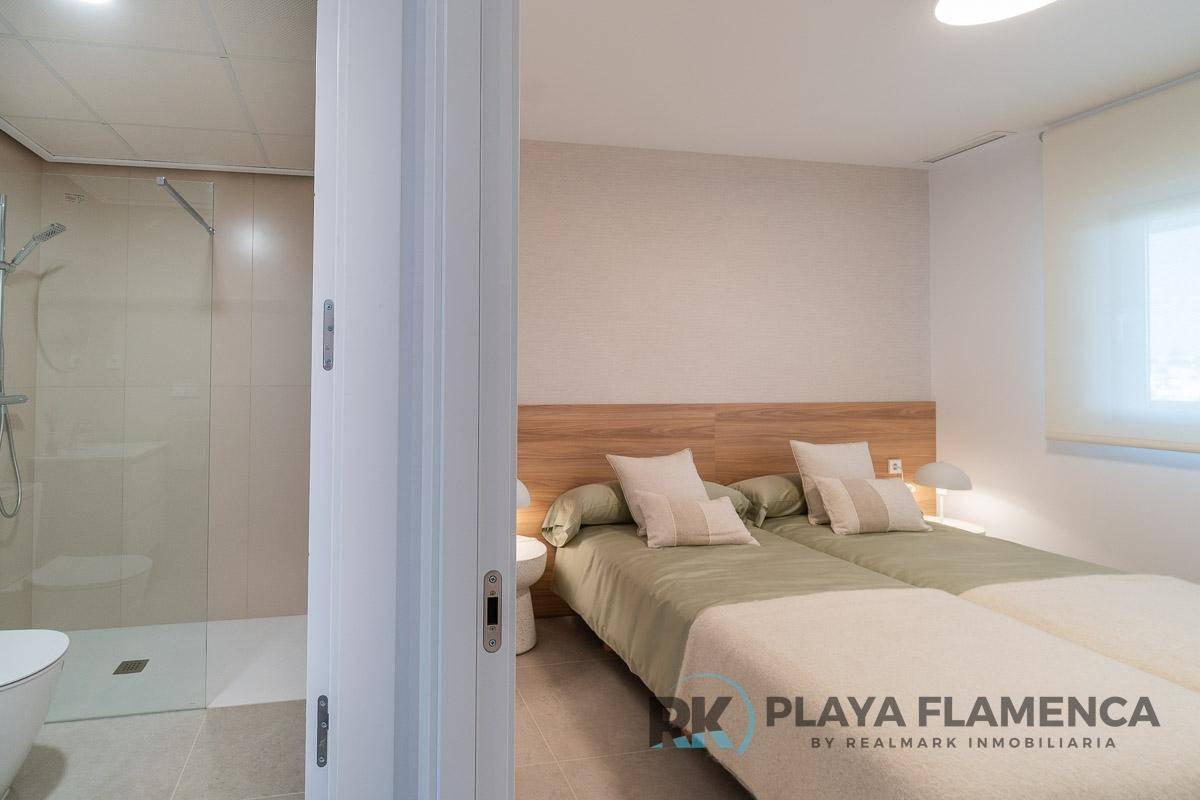Schlafzimmer mit zwei Einzelbetten und Blick auf das angrenzende Badezimmer mit Dusche.