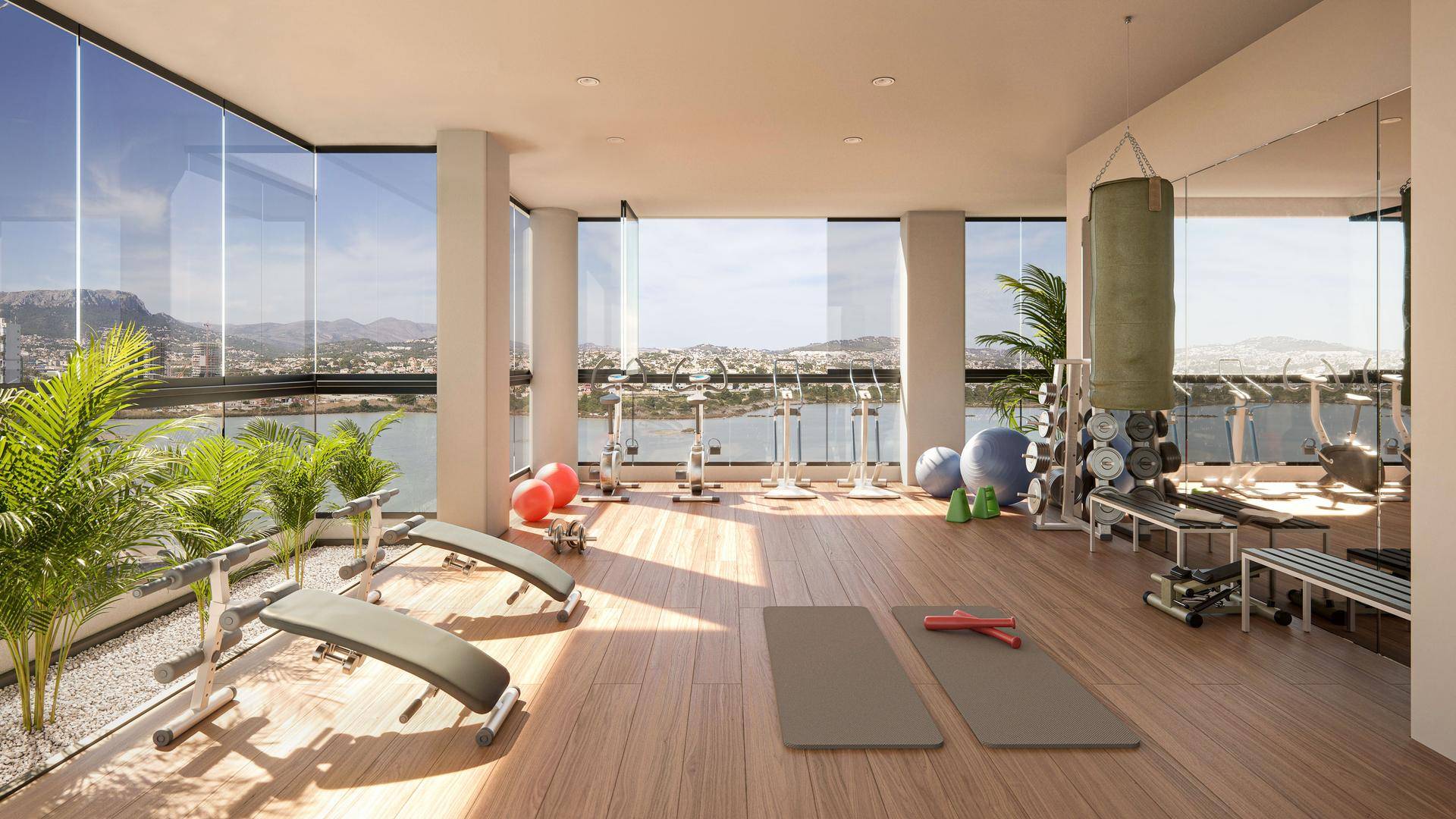 Moderner Fitnessraum mit Trainingsgeräten, großen Fenstern und Blick auf die Landschaft.