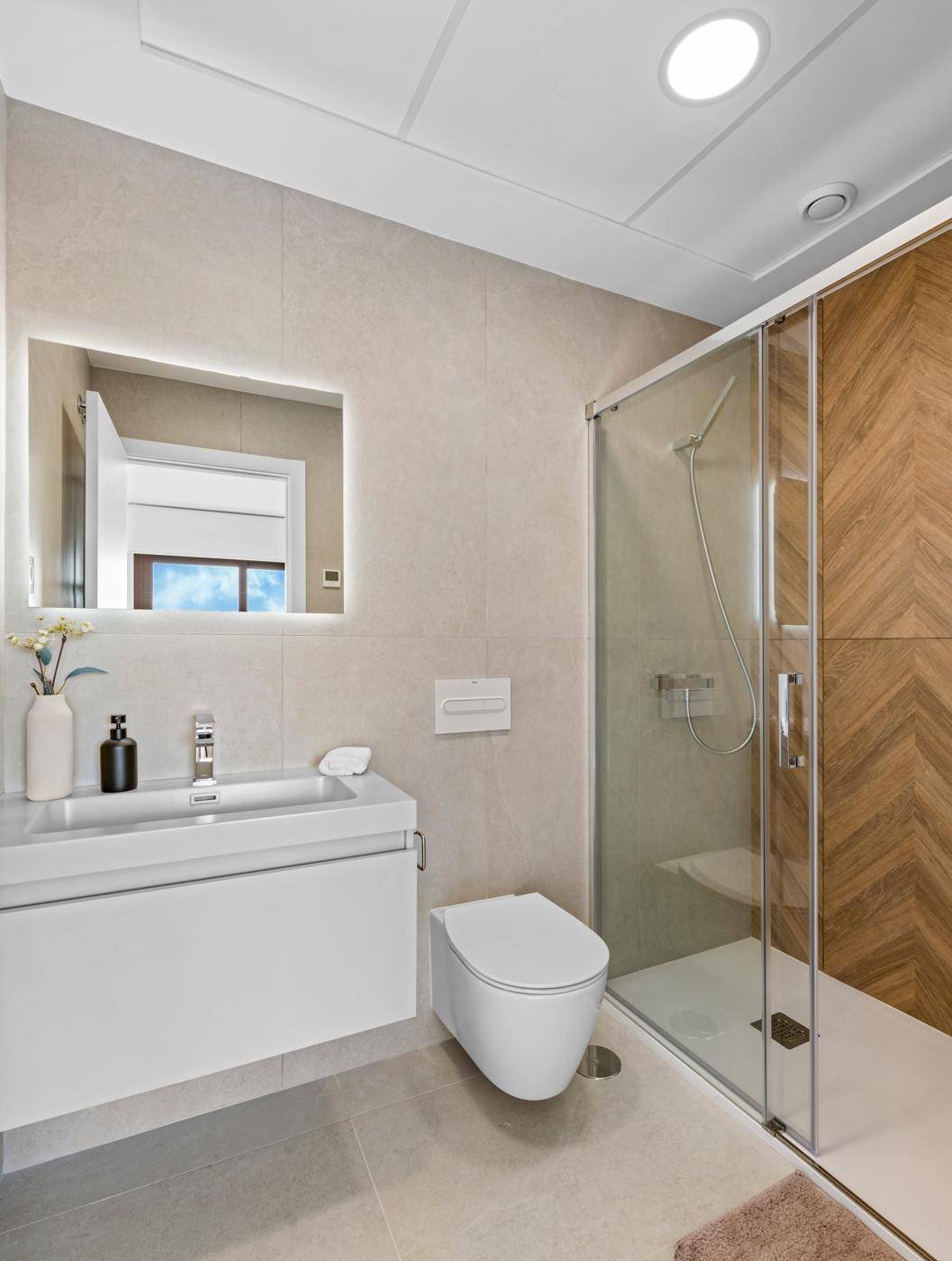 Helles Badezimmer mit moderner Duschkabine, Waschtisch und Wand-WC.