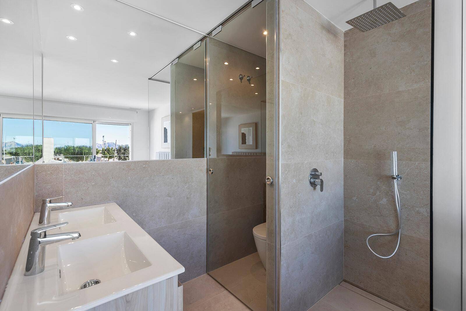 Modernes Badezimmer mit Doppelwaschbecken, großer Spiegelfläche und begehbarer Dusche.