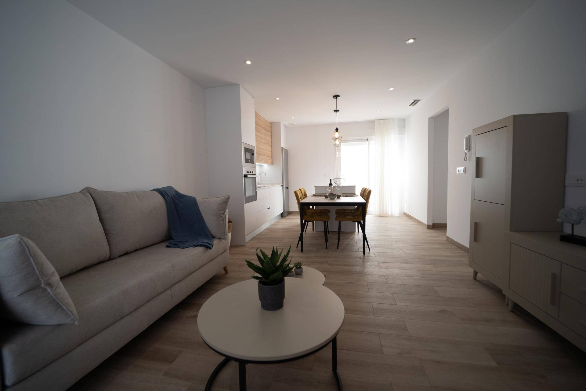 Geräumiger Wohnbereich mit Sofa, Couchtisch und Blick auf den Essbereich und die Küche.