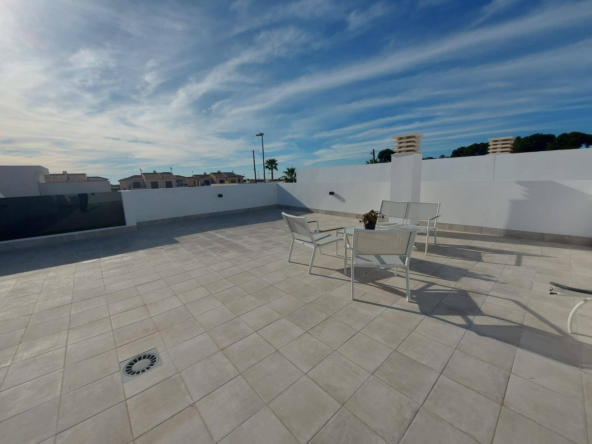 Weitläufige Dachterrasse mit Fliesenboden und Sitzgelegenheiten unter weitem Himmel.