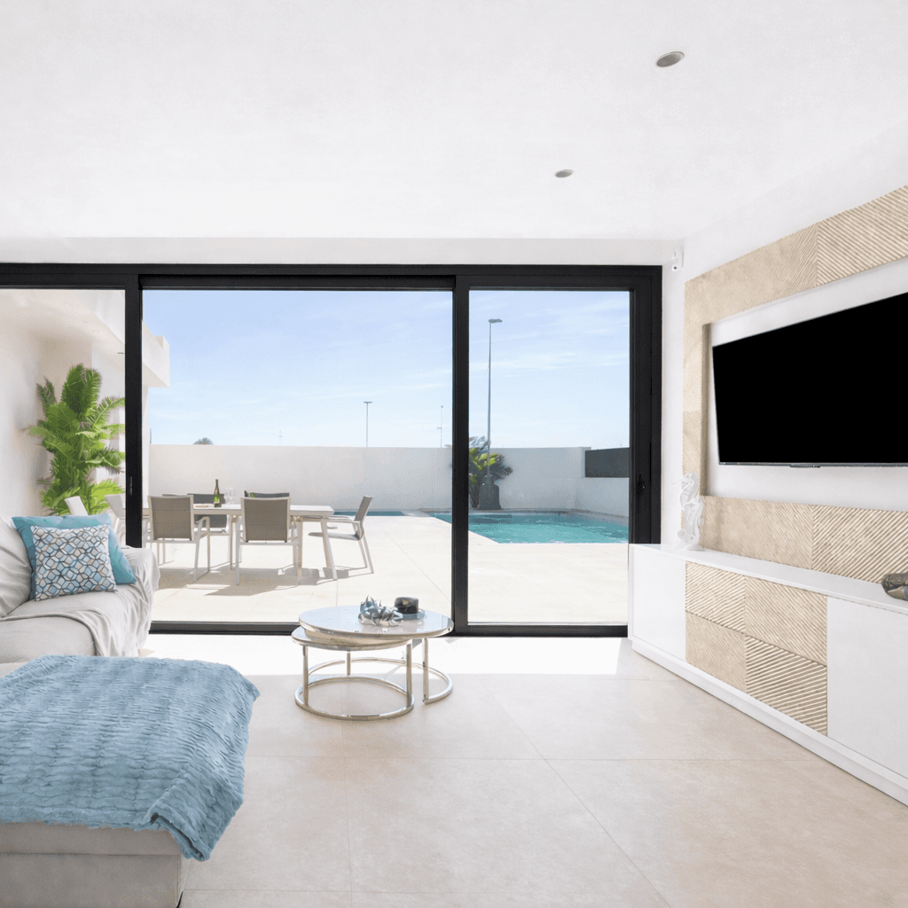 Helles Wohnzimmer mit großen Schiebetüren und Blick auf den Poolbereich.