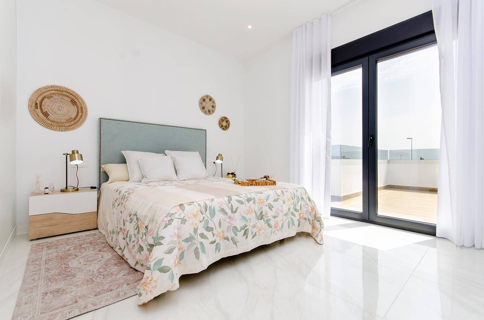 Helles Schlafzimmer mit Doppelbett, großen Fenstern und Zugang zum Balkon.