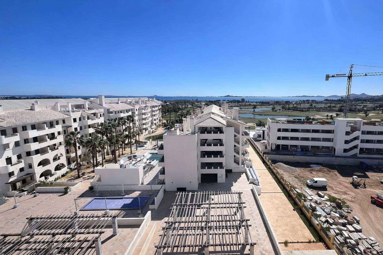 Weitläufige Ansicht eines Apartmentkomplexes mit Golfplatz und Meerblick unter klarem Himmel.