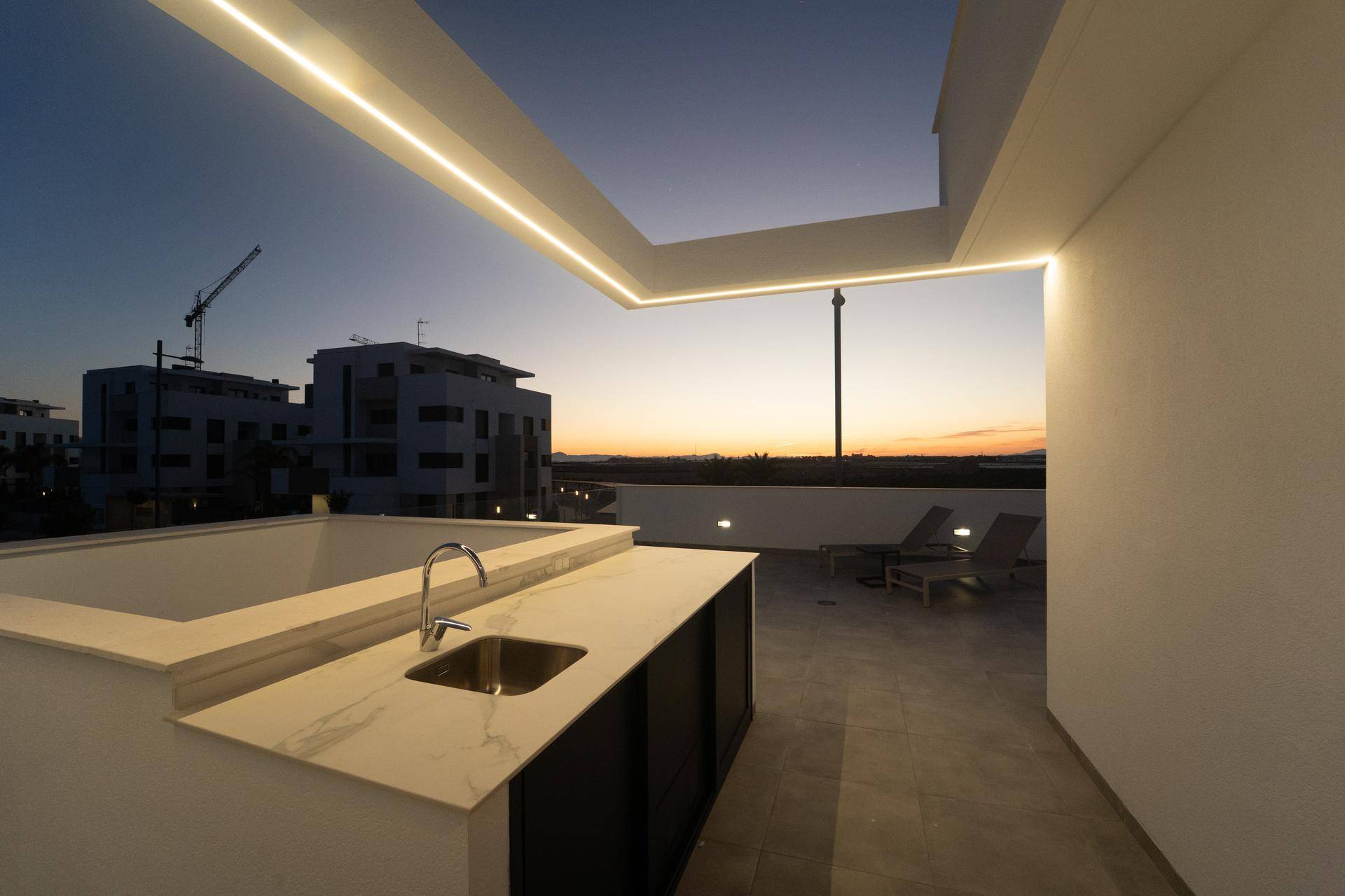 Moderne Dachterrasse mit Außenküche und stimmungsvoller Beleuchtung in der Abenddämmerung.