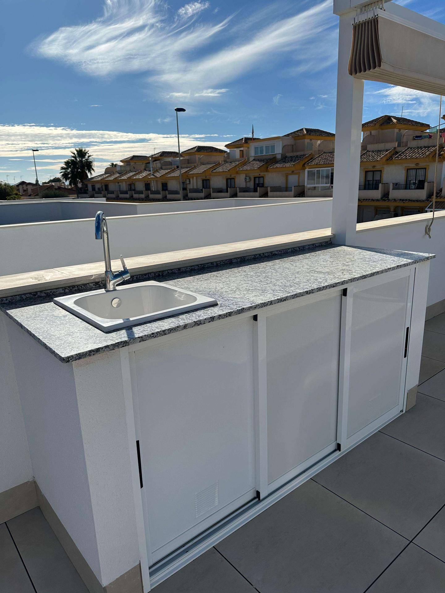 Außenküche mit Spüle und Granitarbeitsplatte auf der sonnigen Dachterrasse.