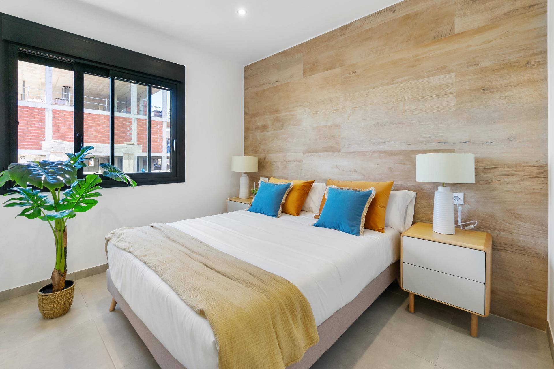 Helles Schlafzimmer mit Holzwandakzent, großem Fenster und modernen Nachttischen.