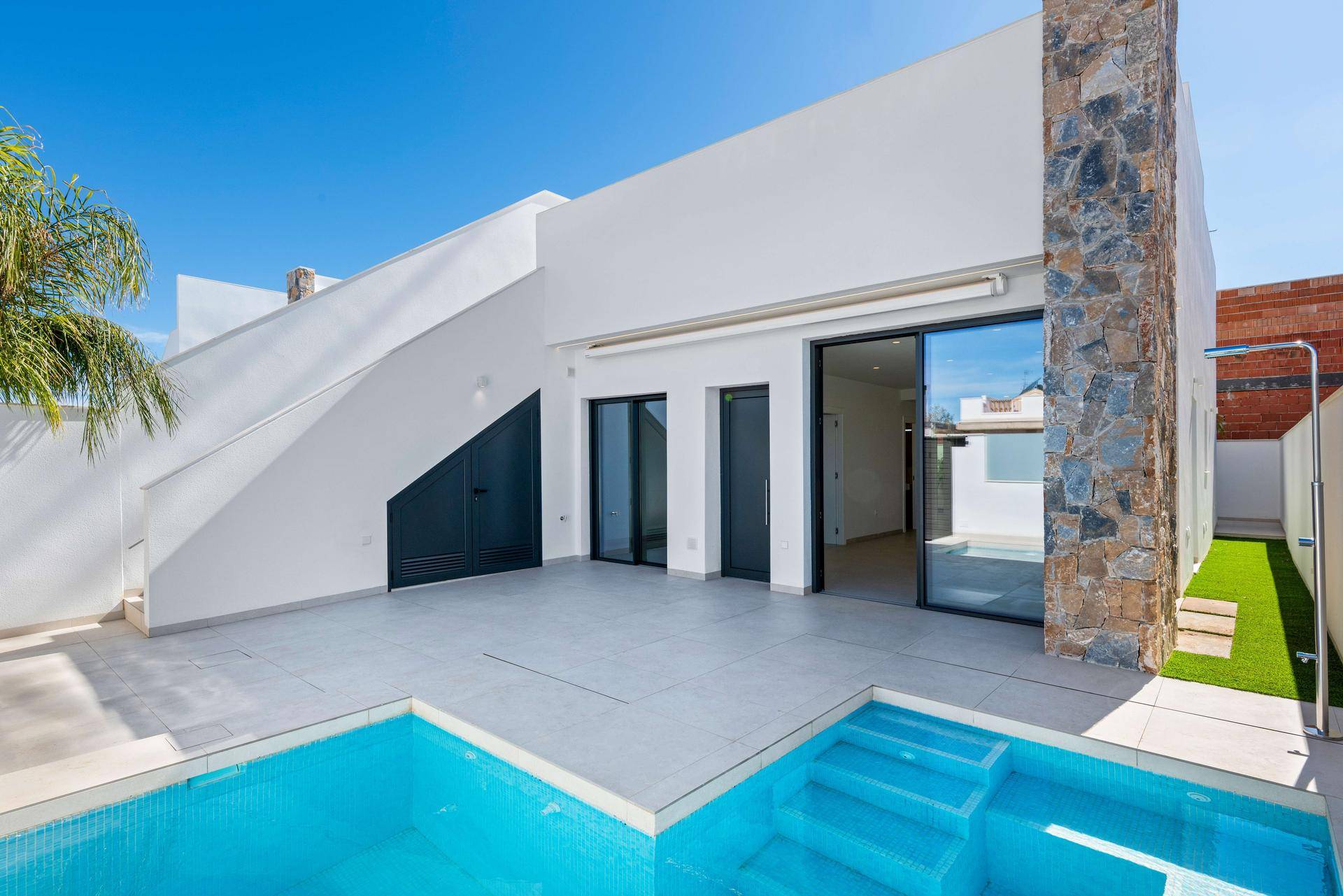 Moderne Villa mit Pool und großzügiger Terrasse, umgeben von klarem Himmel.