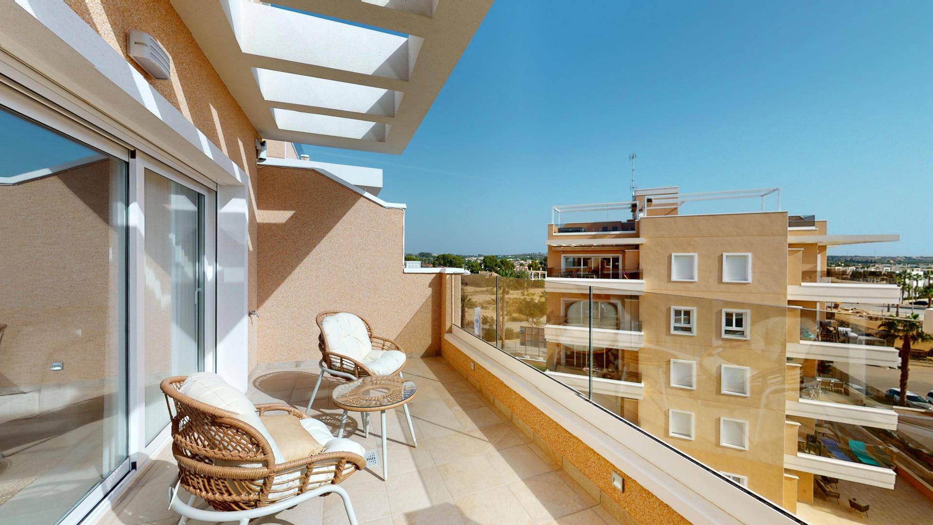 Heller Balkon mit Glasgeländer, Sitzgelegenheiten und weitem Blick über die Umgebung.