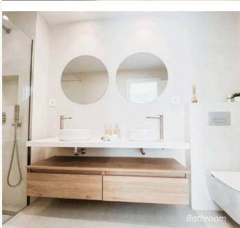 Modernes Badezimmer mit Doppelwaschbecken, runden Spiegeln und begehbarer Dusche.