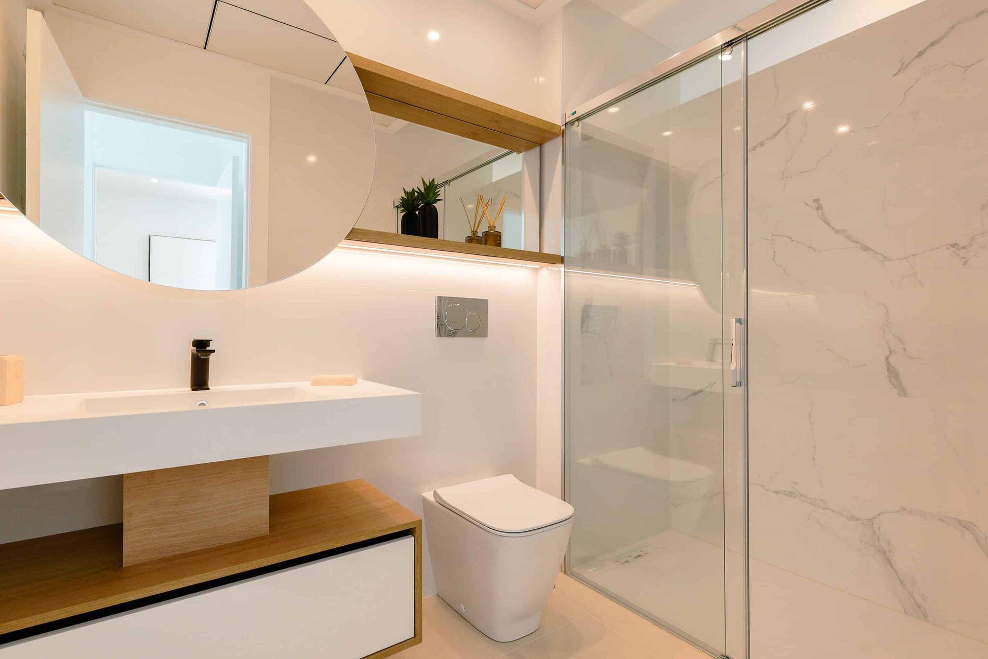 Modernes Badezimmer mit begehbarer Dusche, wandhängendem WC und eleganten Marmorfliesen.