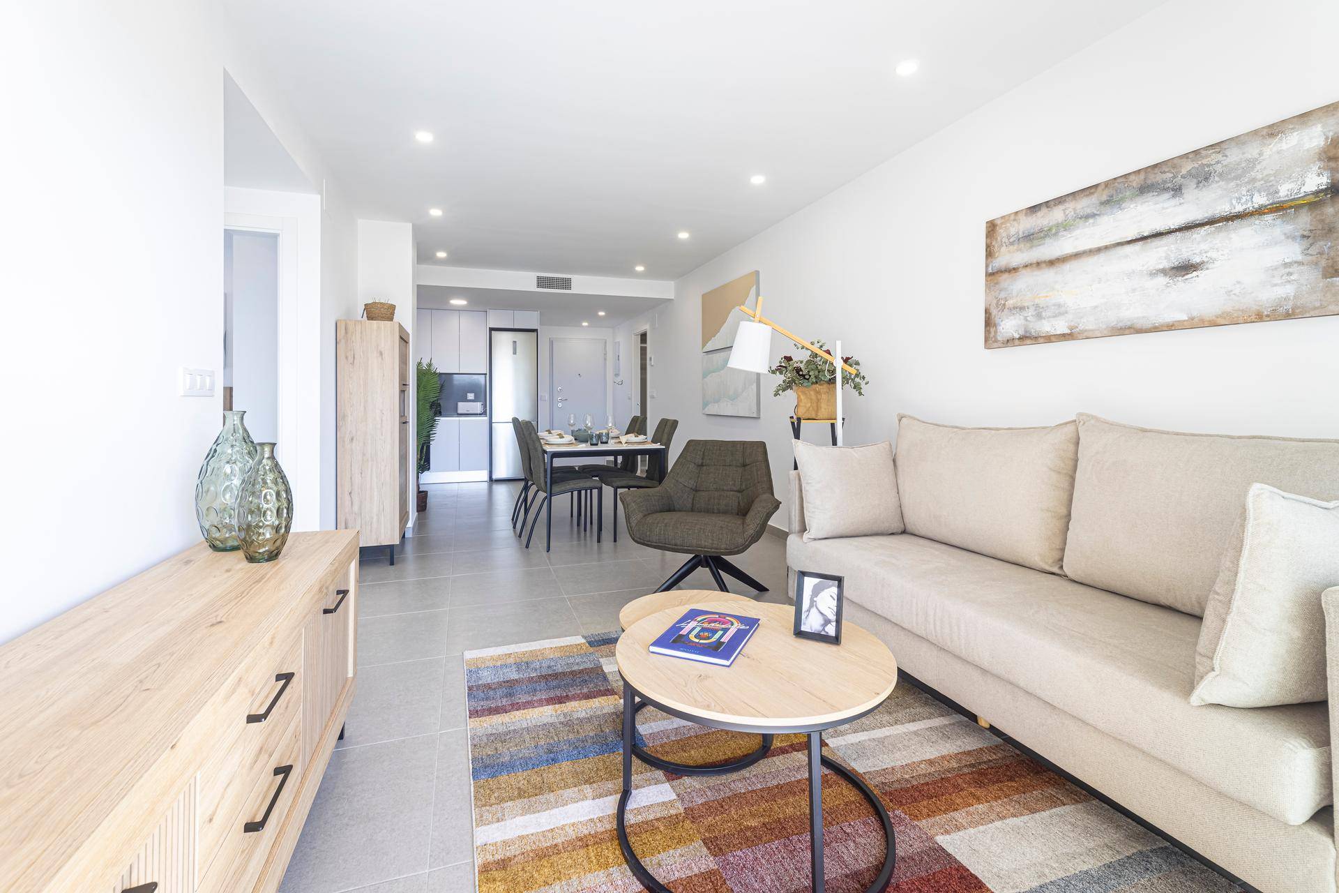 Gemütliches Wohnzimmer mit heller Couch, Couchtisch und farbenfrohem Teppich.