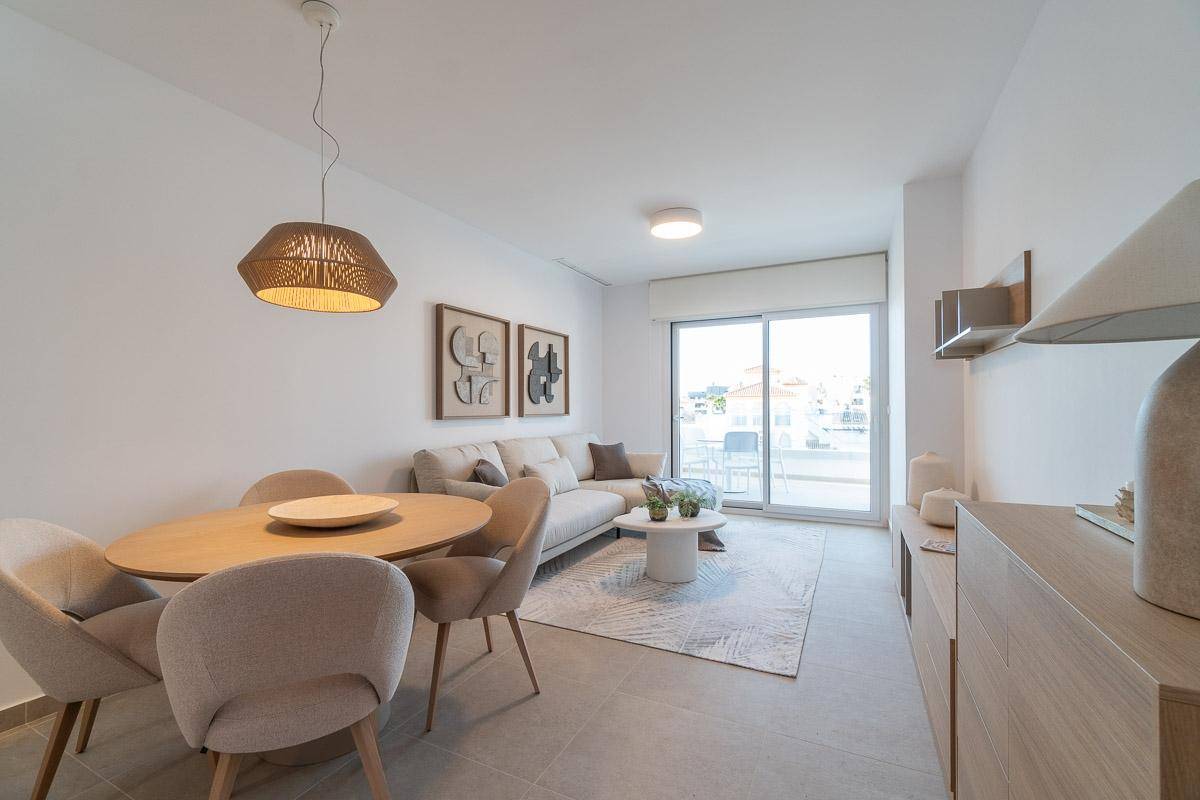 Geräumiger Wohn-Essbereich mit beigem Sofa, Esstisch und Zugang zu einem sonnigen Balkon.