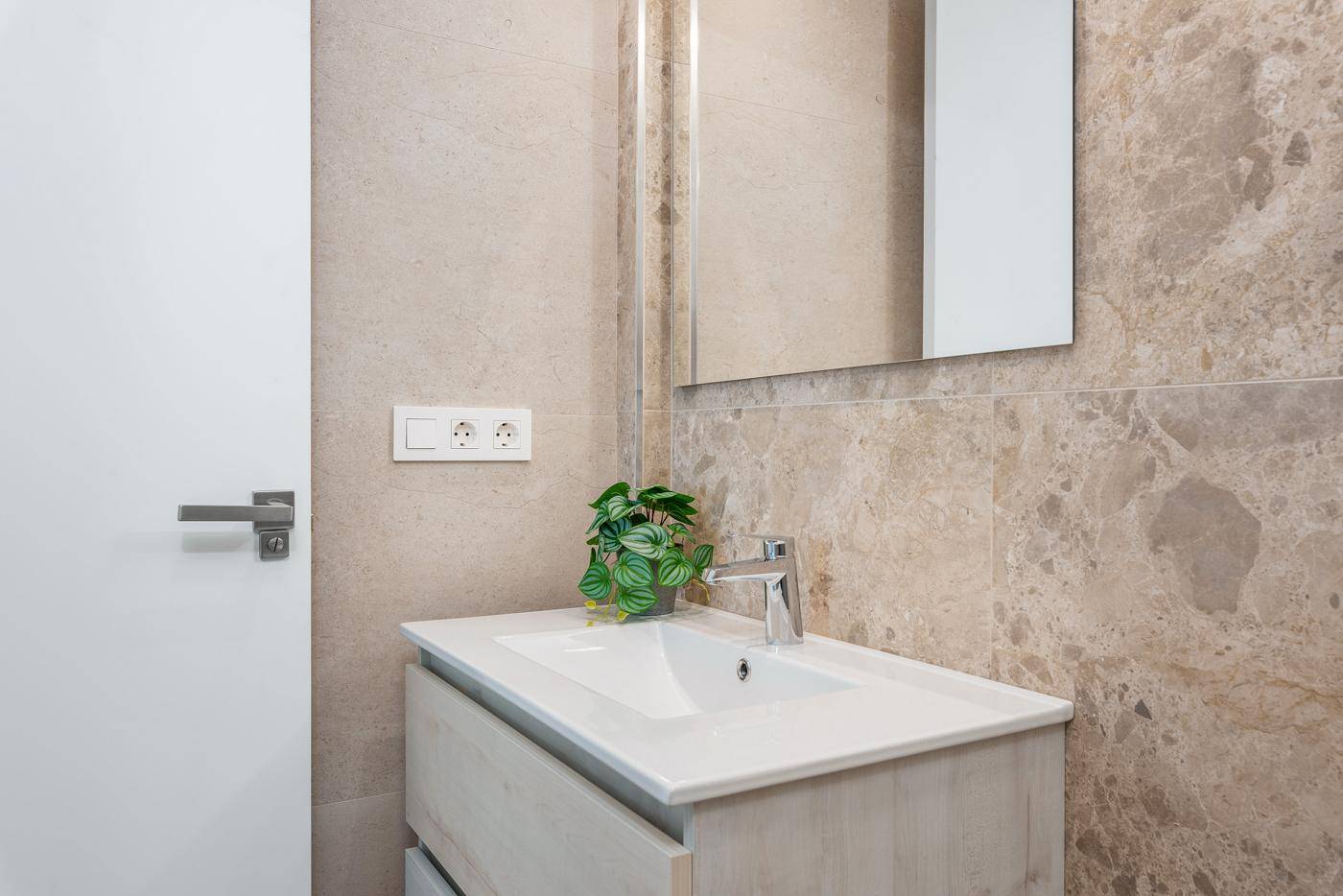 Modernes Badezimmer mit Einzelwaschbecken und Natursteinfliesen an der Wand.