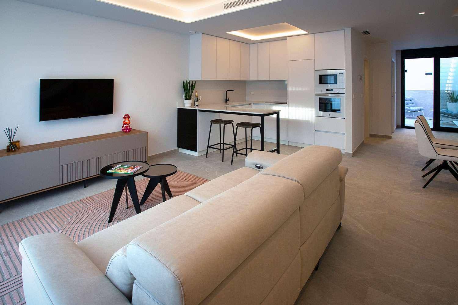 Heller offener Wohnbereich mit integrierter Küche, beigem Sofa und direktem Zugang zur Terrasse.
