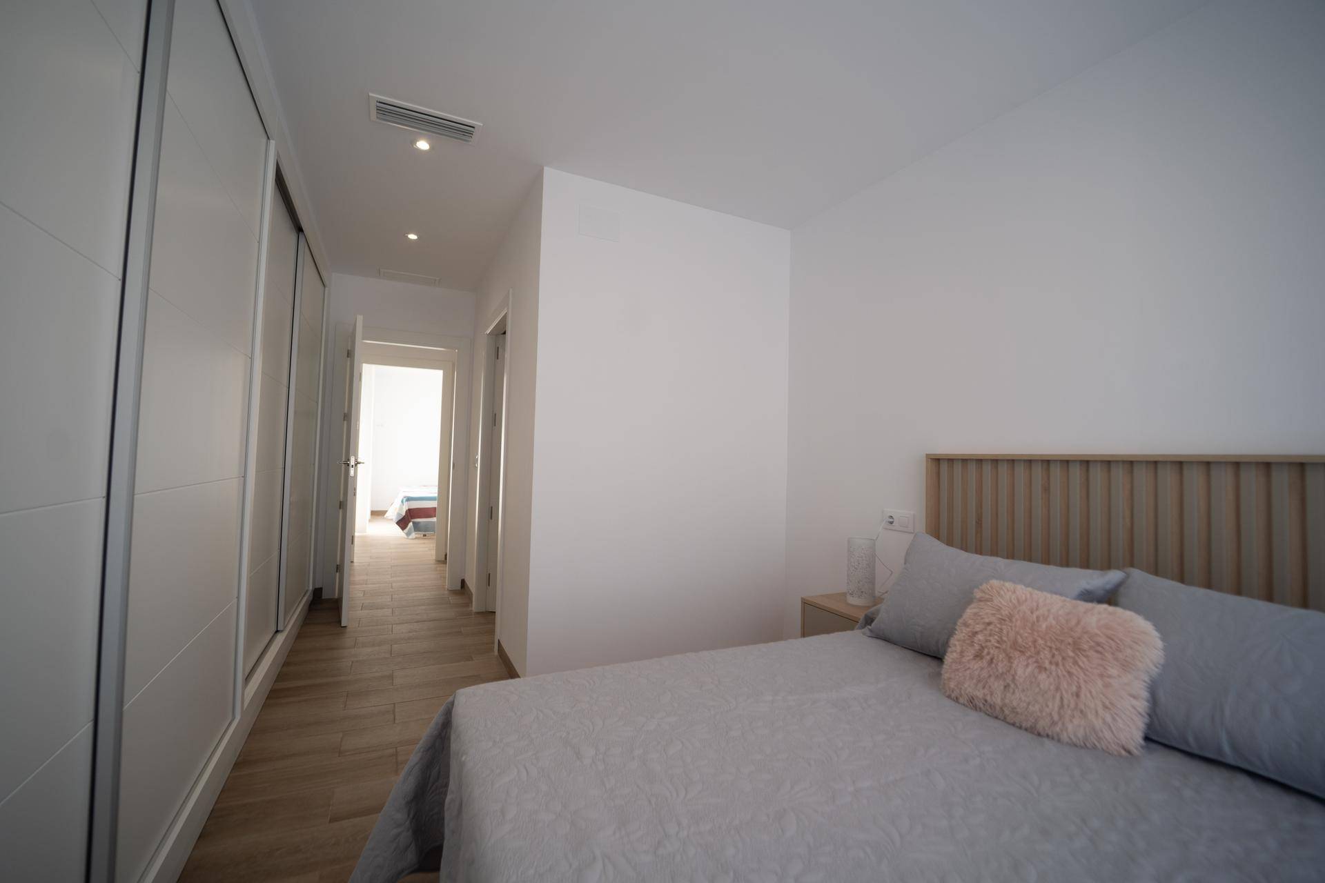Modernes Schlafzimmer mit großem Bett und integrierten weißen Kleiderschränken entlang der Wand.