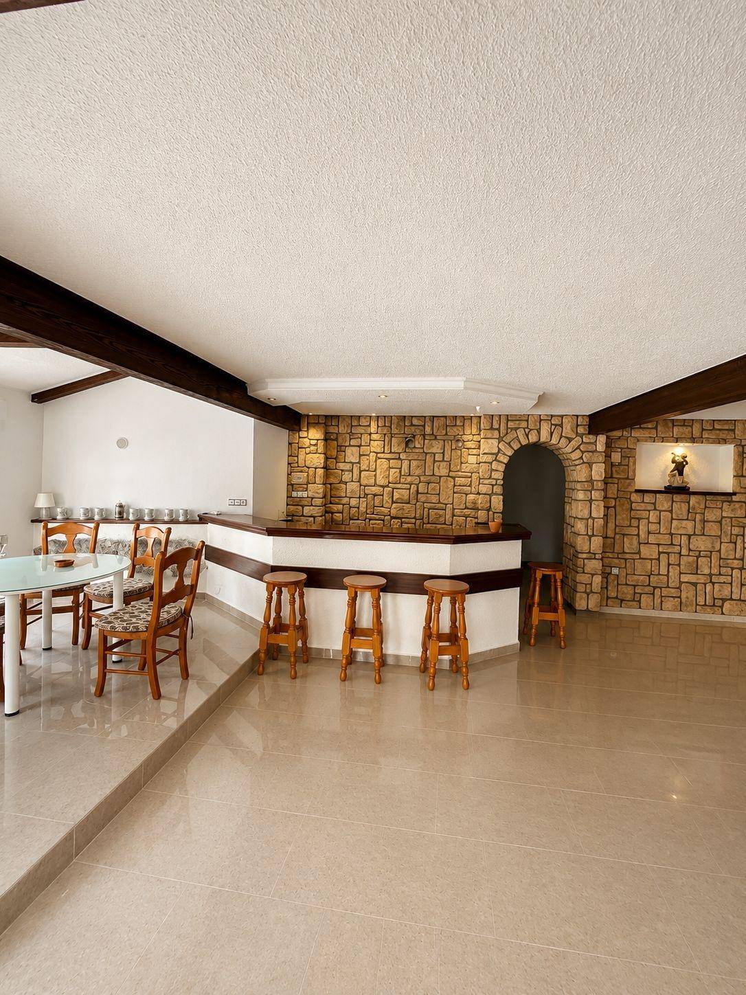Großer offener Raum mit Bar, Steinwand und Essbereich, ideal für Unterhaltung.