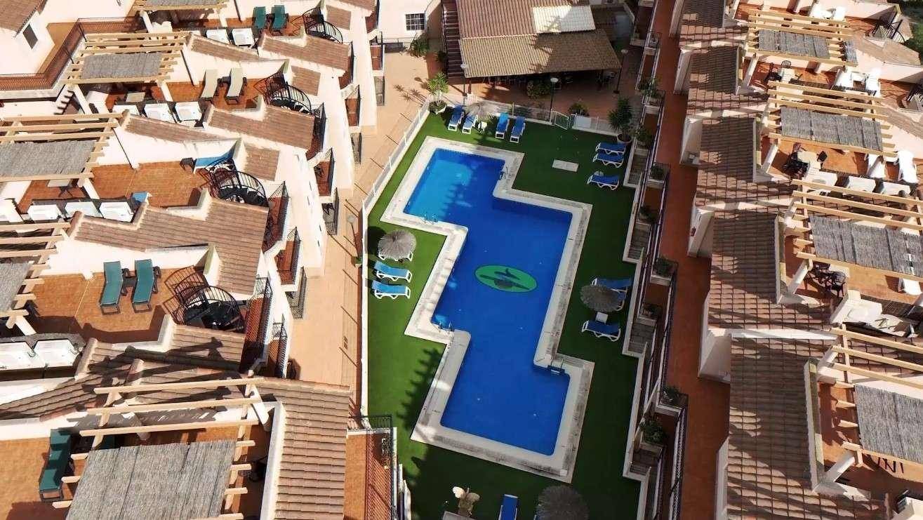 Vogelperspektive auf den Poolbereich der Wohnanlage, umgeben von den Gebäuden.