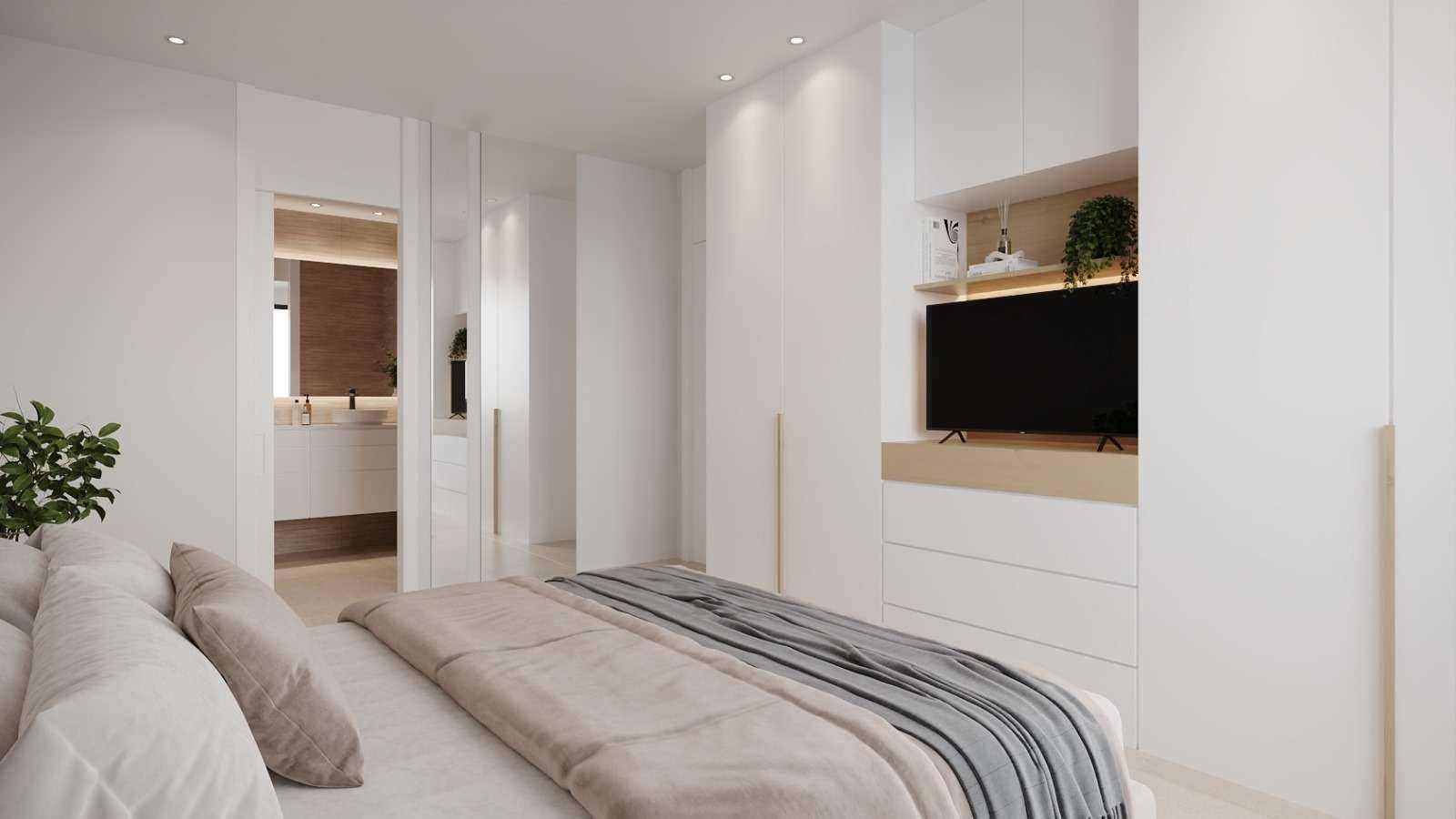 Schlafzimmer mit integrierten Schränken und Blick auf ein modernes Badezimmer mit Doppelwaschbecken.