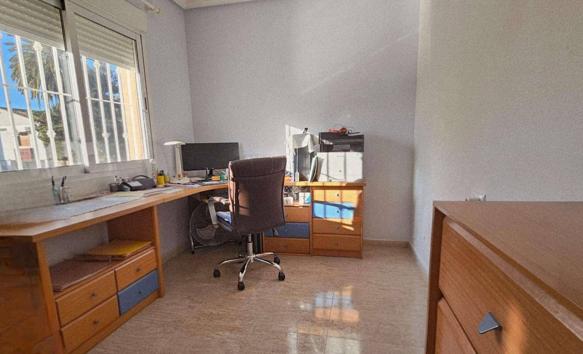Helles Arbeitszimmer mit Schreibtisch, Bürostuhl und Fenster mit Blick nach draußen.