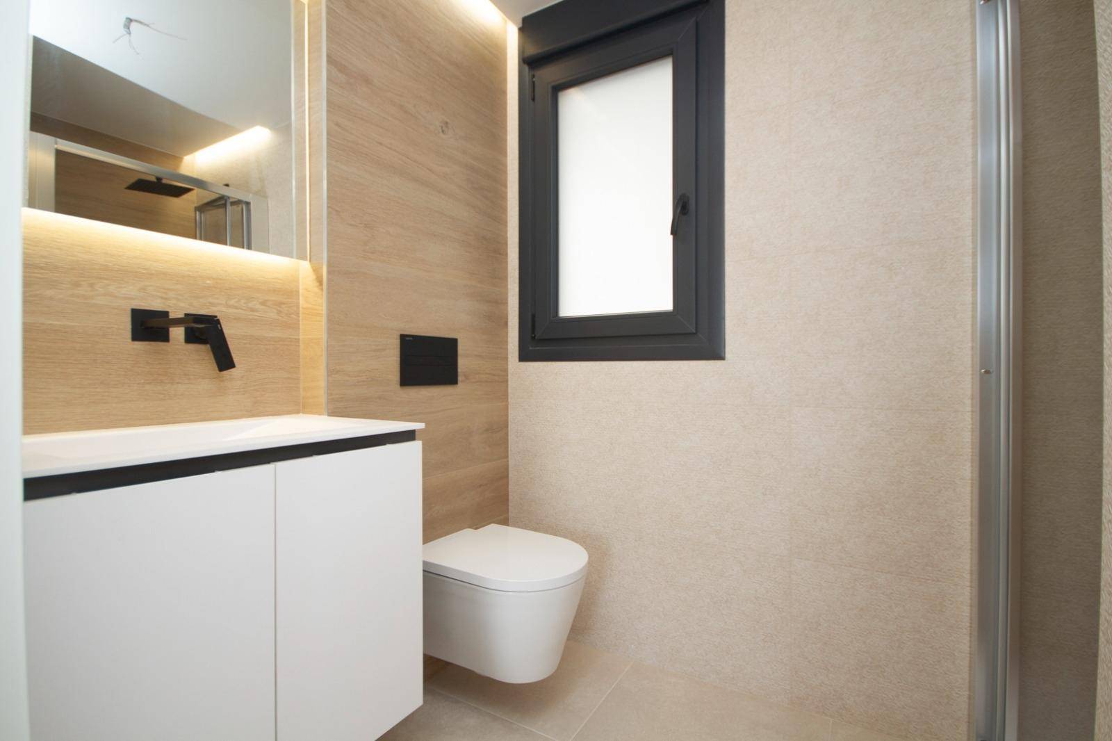 Modernes Badezimmer mit wandhängendem WC, Waschtisch und begehbarer Dusche.