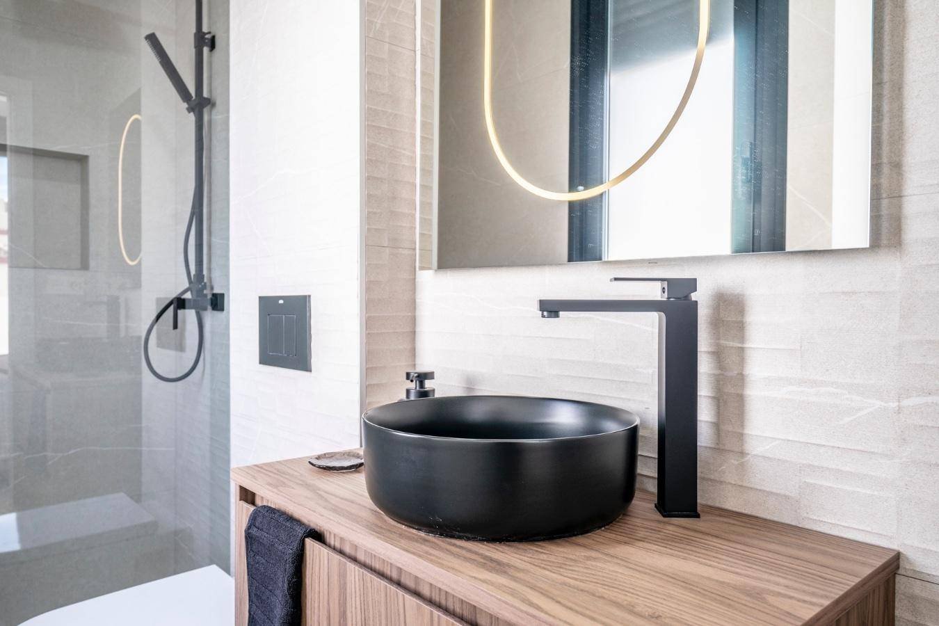 Modernes Badezimmer mit schwarzem Aufsatzwaschbecken, dunklen Armaturen und einer begehbaren Dusche.