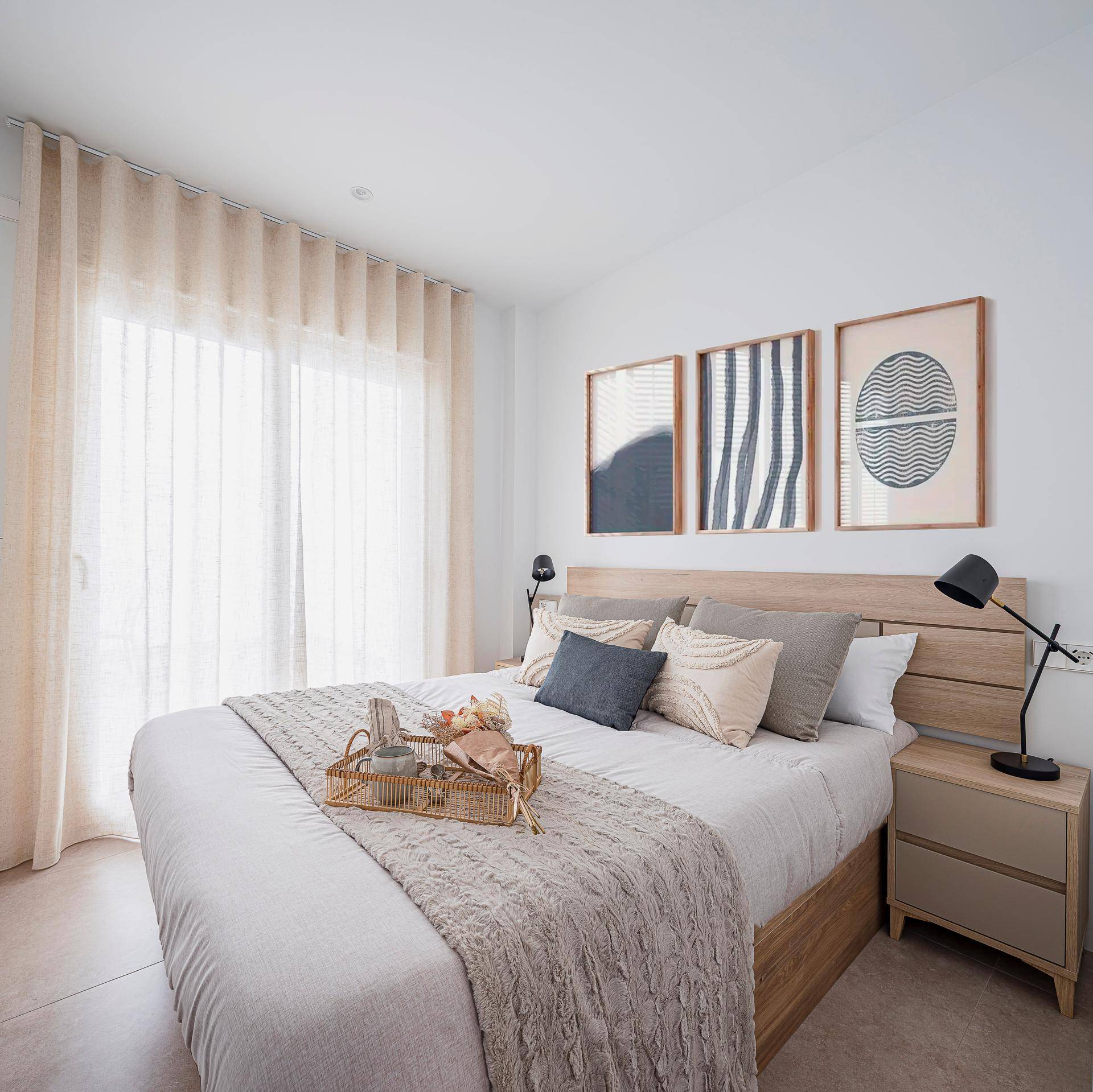 Helles Schlafzimmer mit Doppelbett, Holzkopfteil und Zugang zu einem sonnigen Balkon.