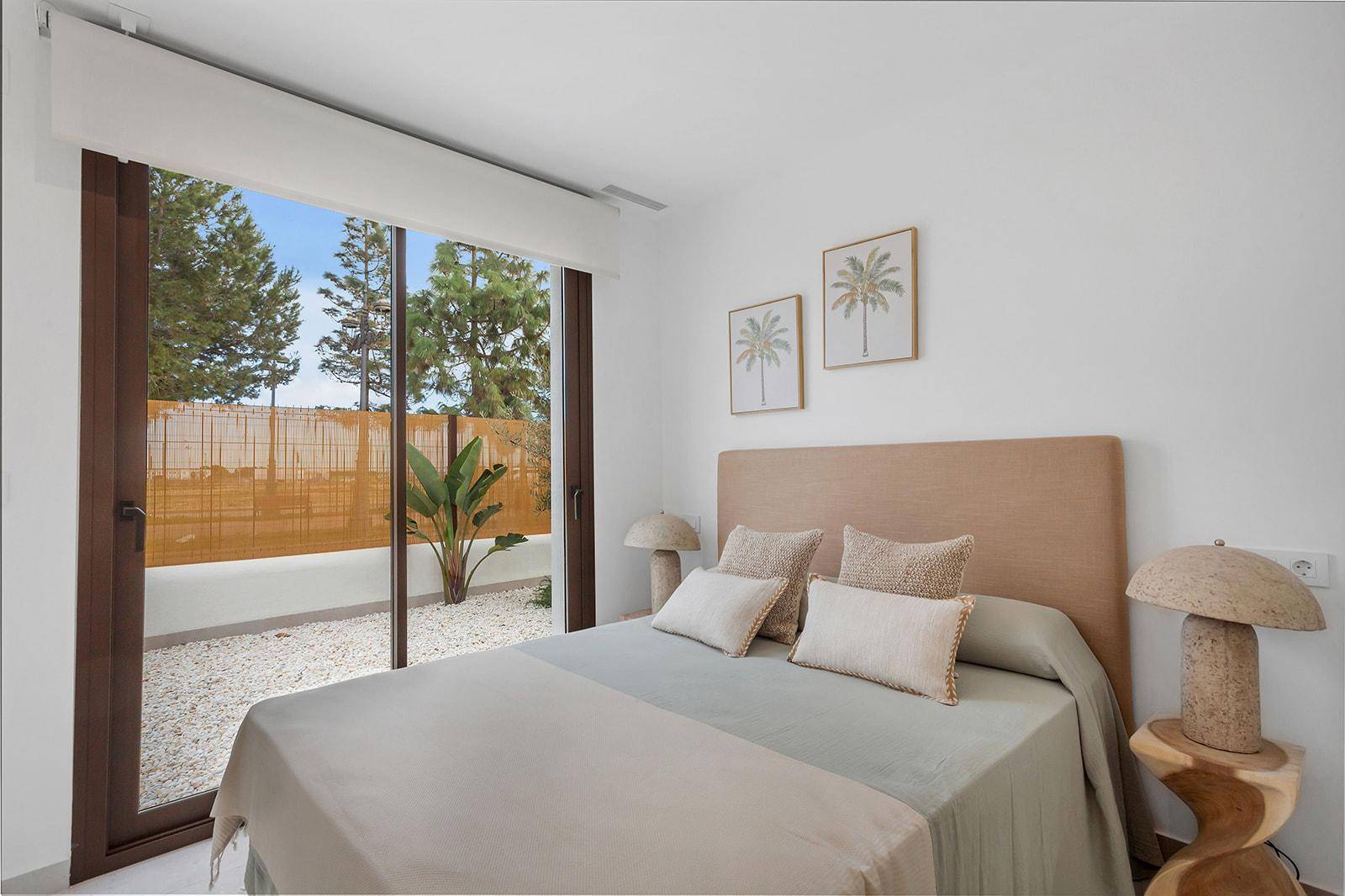Schlafzimmer mit großem Fenster, das auf einen privaten Kiesgarten blickt.