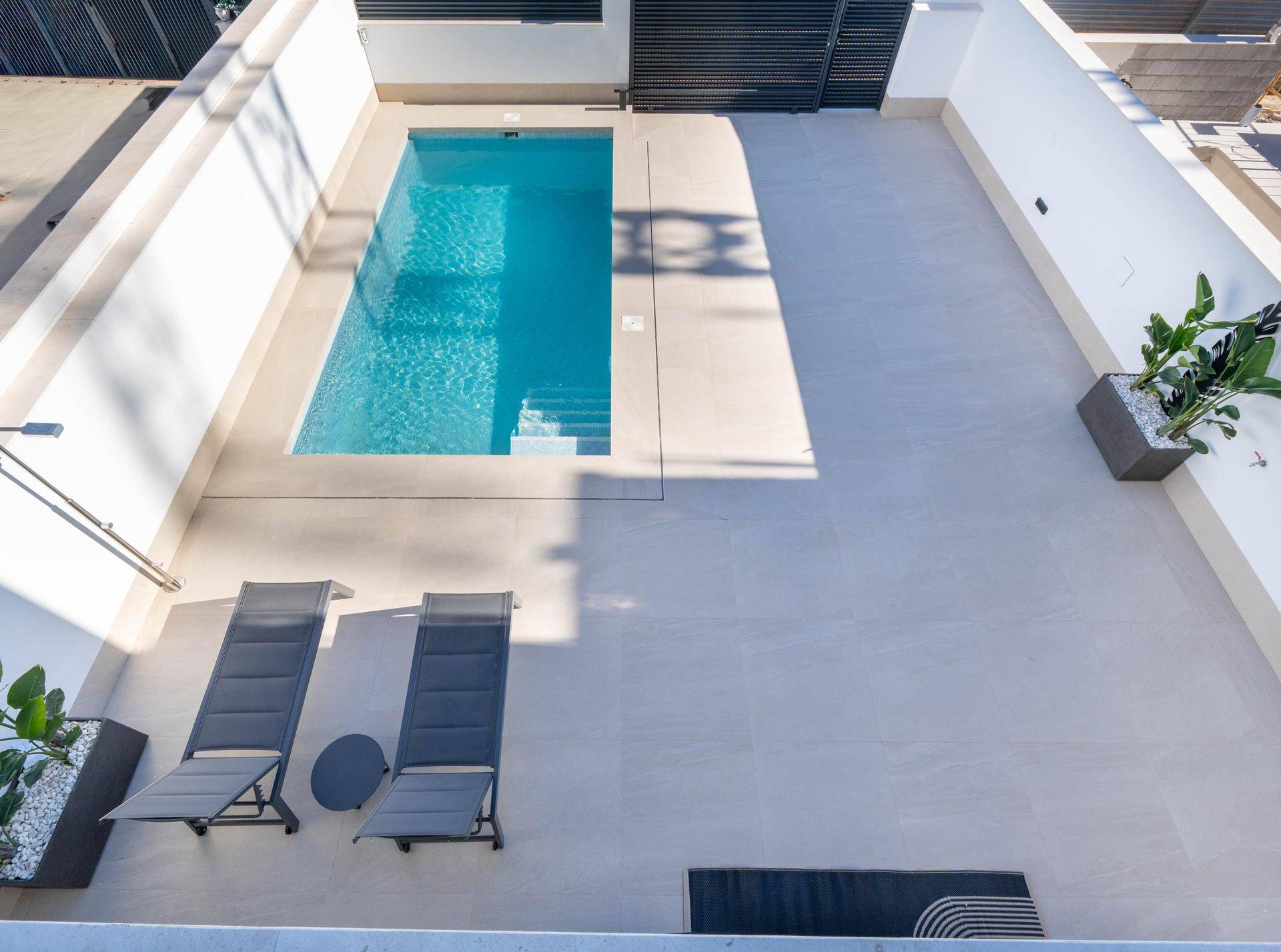Vogelperspektive auf den privaten Pool und die weitläufige Terrasse mit Liegestühlen.