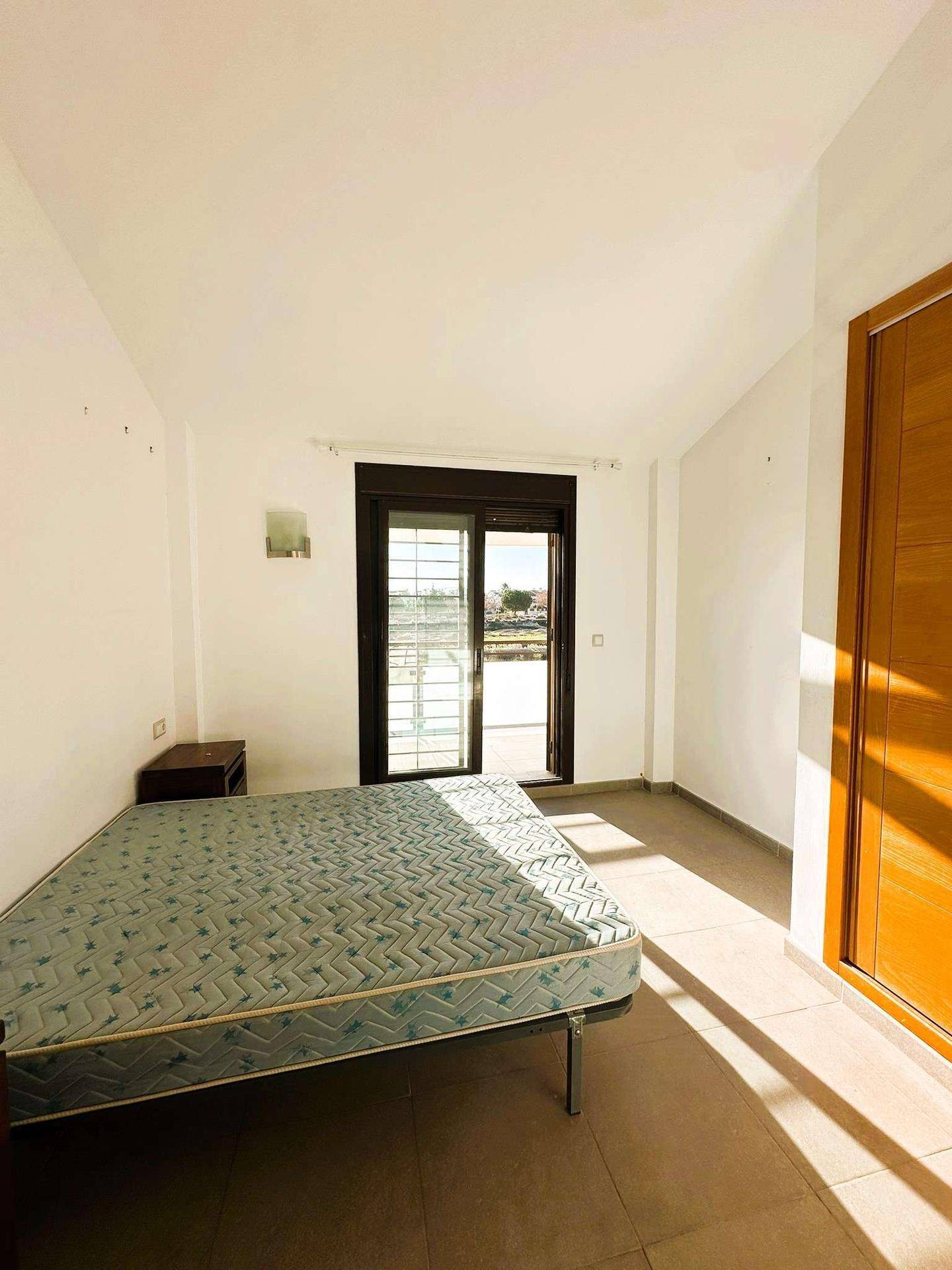 Helles Schlafzimmer mit Fliesenboden, Balkonzugang und viel natürlichem Licht.