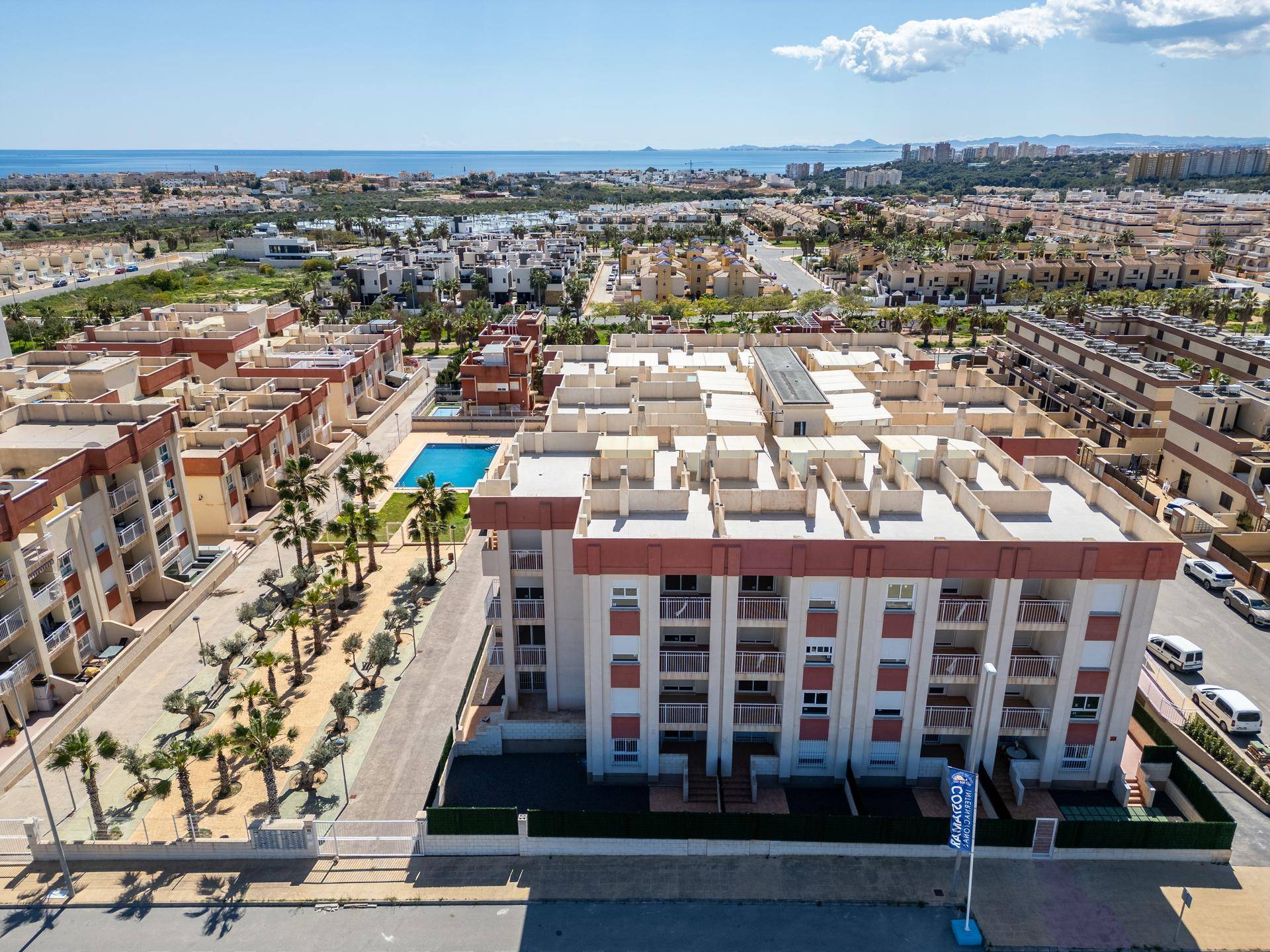 Panoramablick auf den Wohnkomplex mit Poolbereich und dem weiten Meer am Horizont.