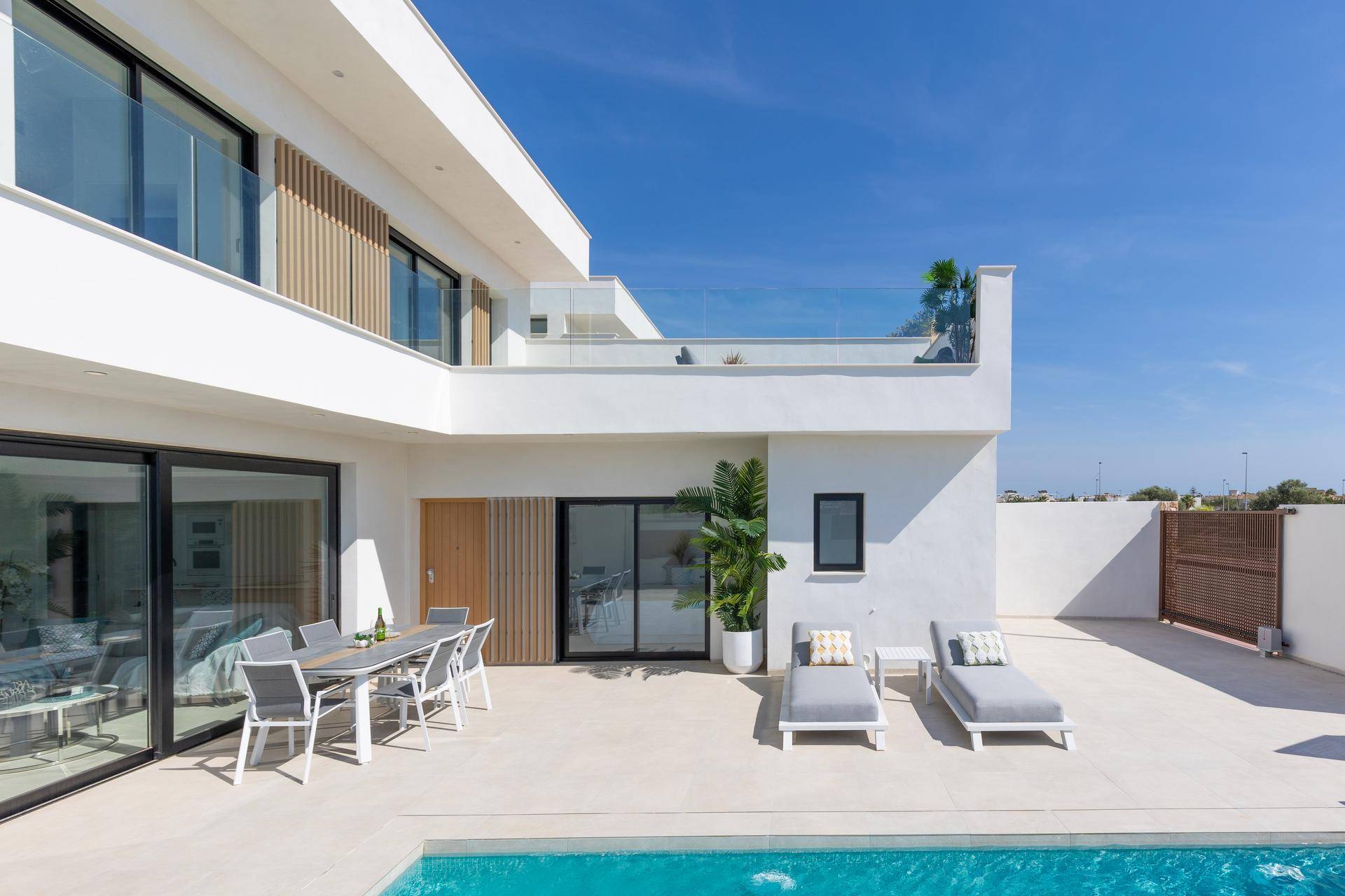 Geräumige Terrasse mit Pool, Liegestühlen und Esstisch vor der modernen Villa.