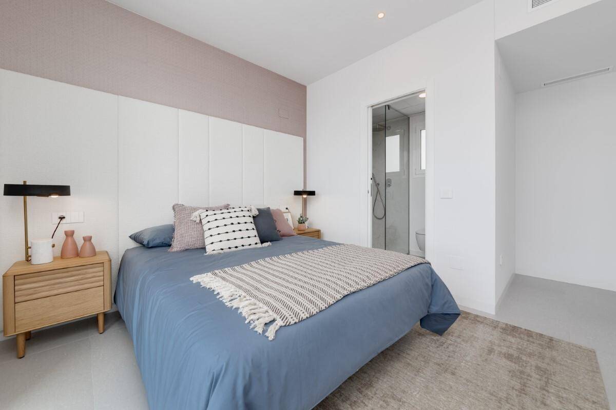 Modernes Schlafzimmer mit Doppelbett, Nachttischen und Zugang zu einem Duschbad.