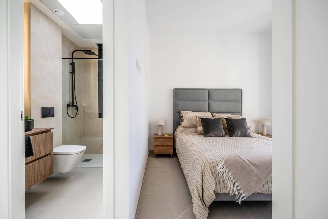 Schlafzimmer mit Doppelbett und direktem Zugang zu einem modernen Badezimmer mit Dusche.