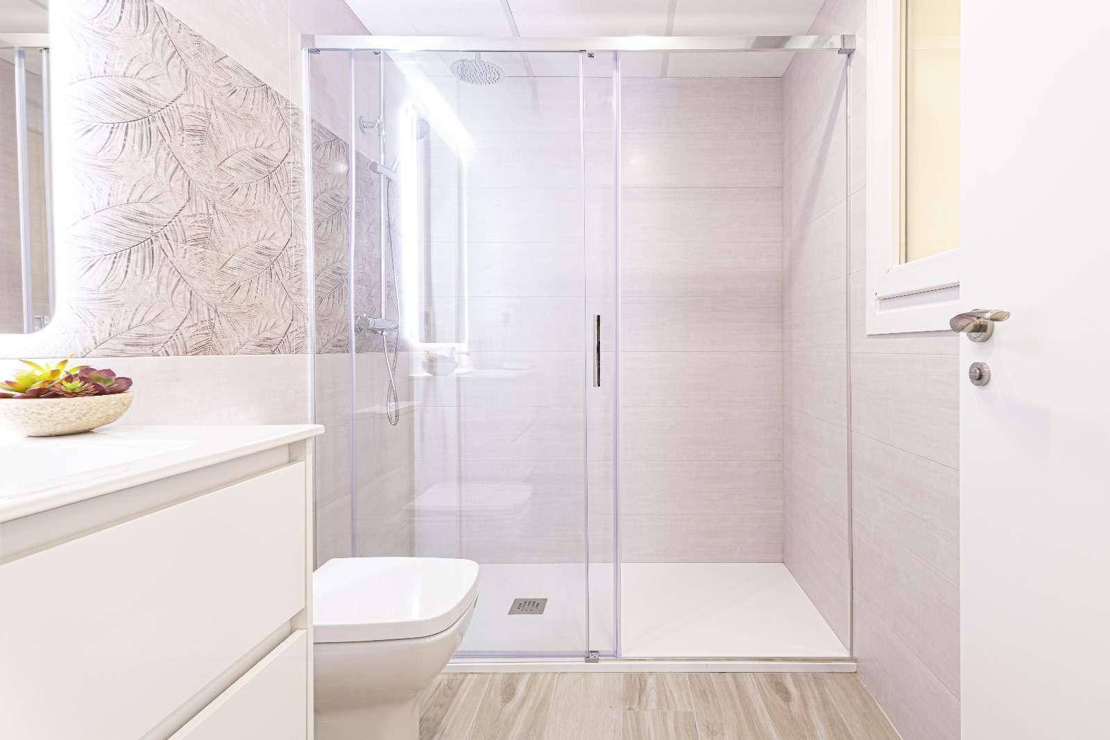 Modernes Badezimmer mit geräumiger Duschkabine, Waschtisch und hellen Fliesen.