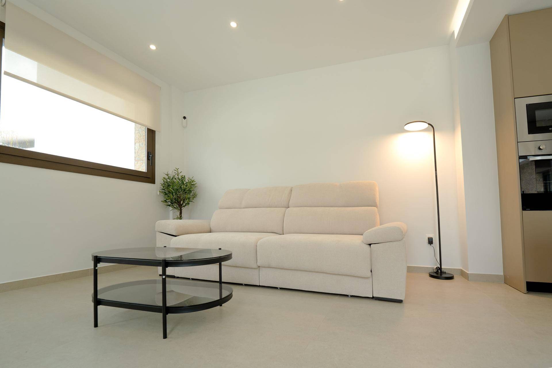 Heller Wohnbereich mit bequemem Zweisitzer-Sofa und Stehlampe, bietet eine entspannte Atmosphäre.