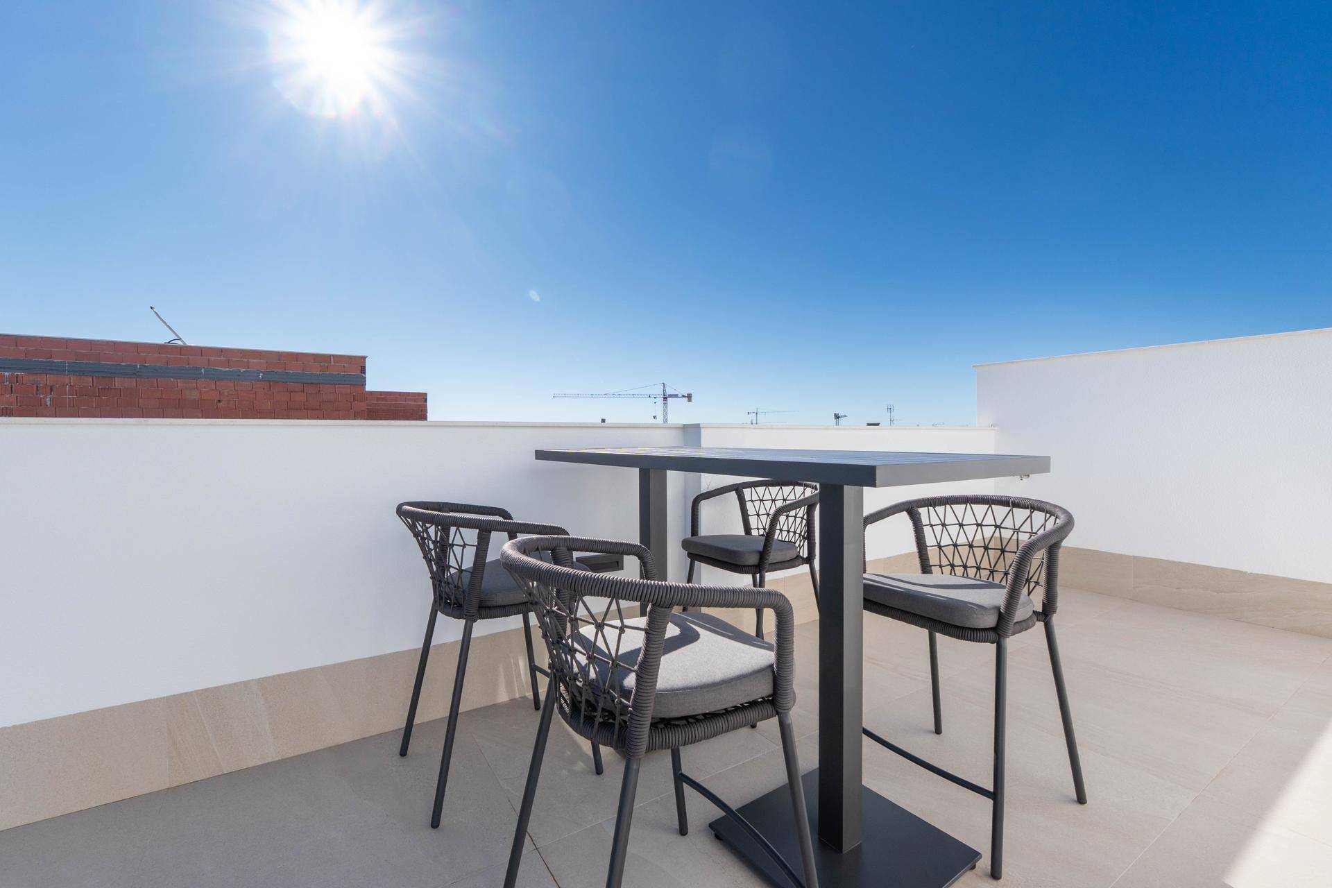 Sonnige Dachterrasse mit modernem Bartisch und Stühlen, ideal für Mahlzeiten im Freien.