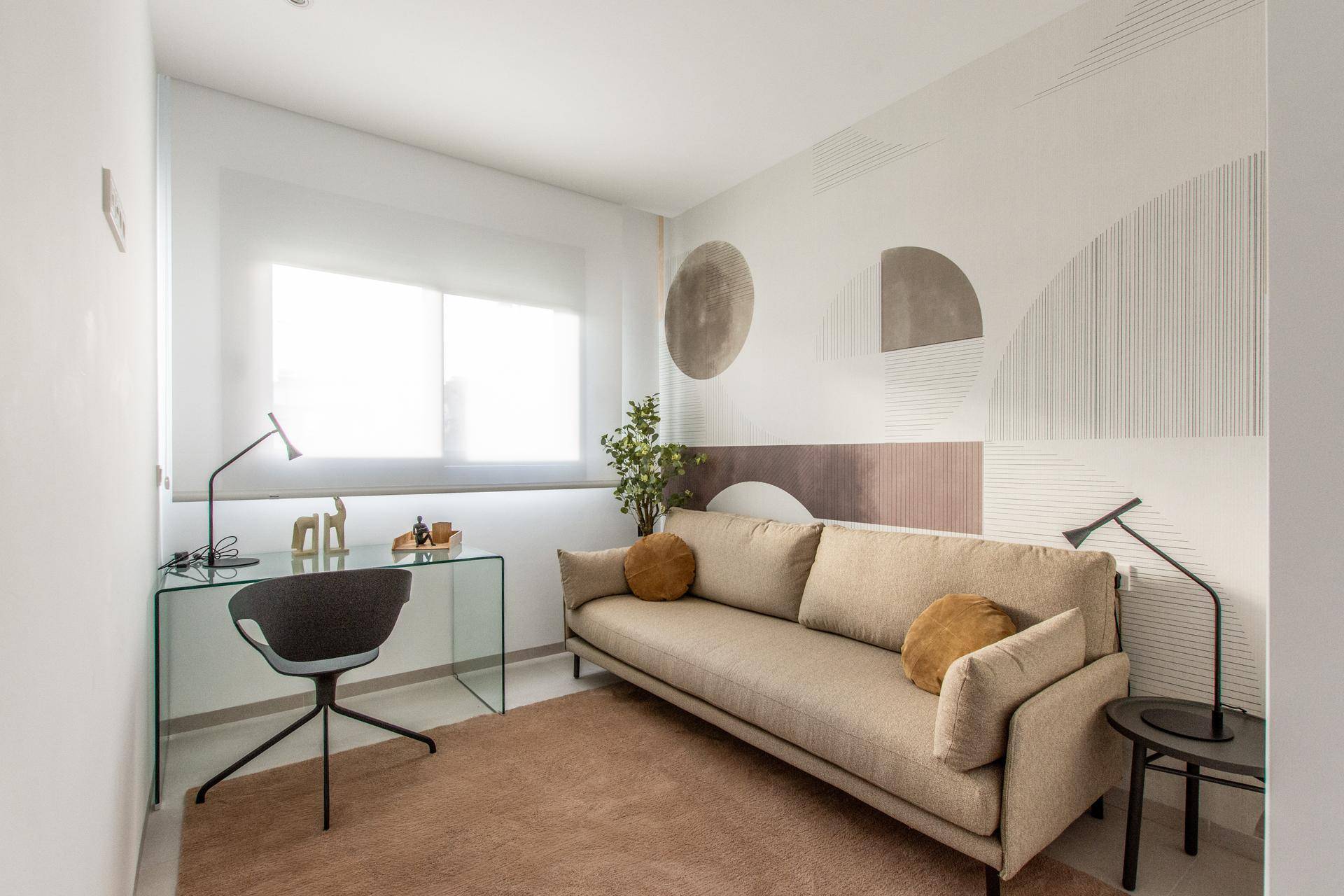 Modernes Arbeitszimmer mit Sofa, Glasschreibtisch und dekorativer Wandgestaltung.