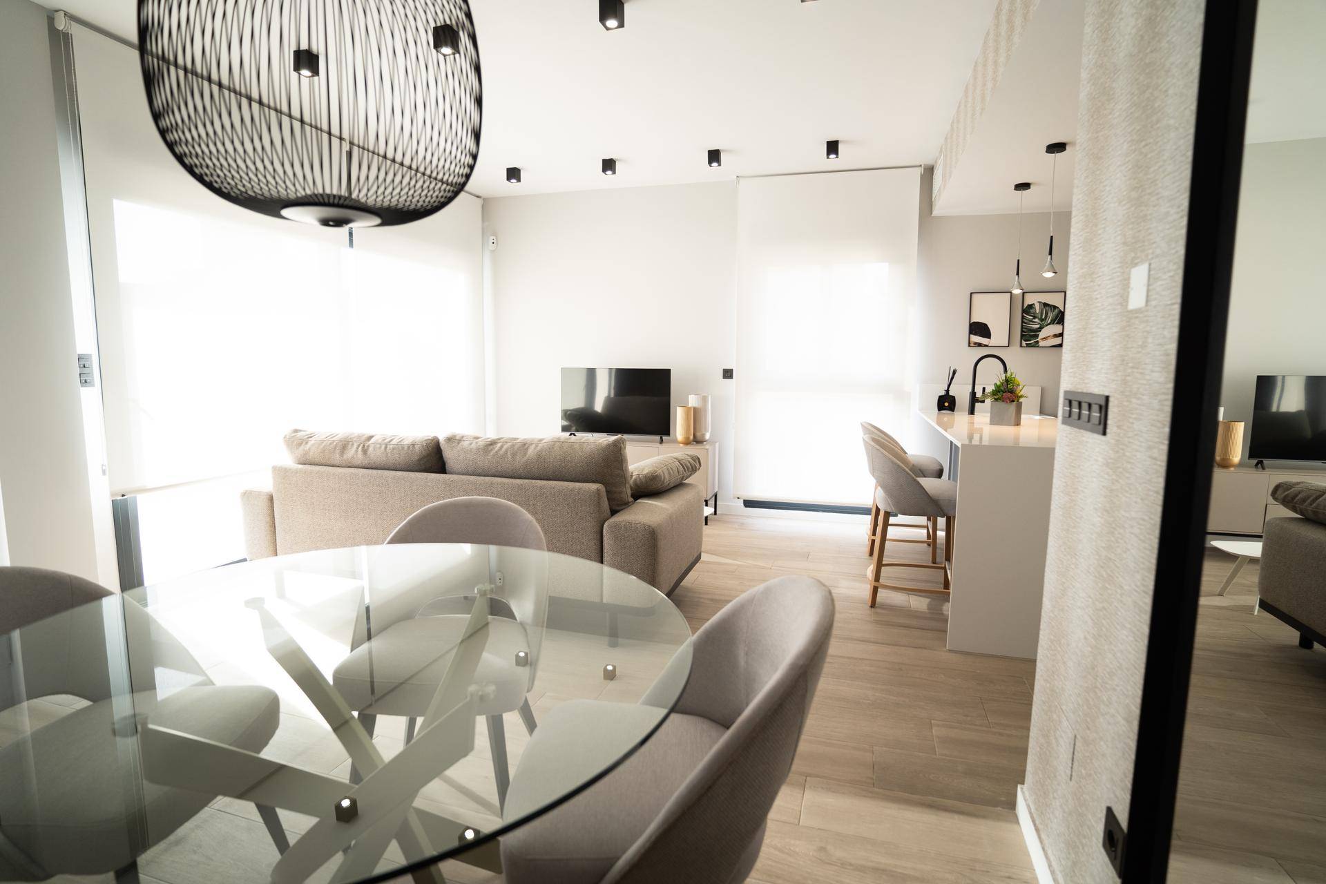 Geräumiger Wohn-Essbereich mit Glastisch, Sofa und offener Küche.