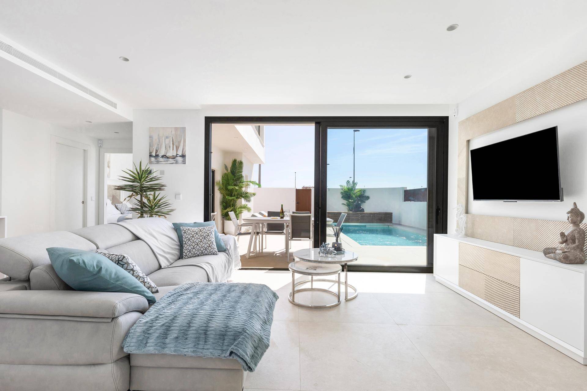 Helles Wohnzimmer mit großem Sofa, modernen Möbeln und Blick auf den Poolbereich.