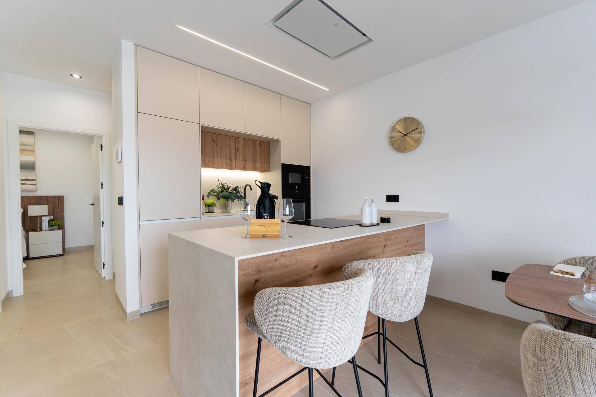 Moderne Küche mit Kücheninsel, Barhockern und integrierten Geräten in hellem Design.