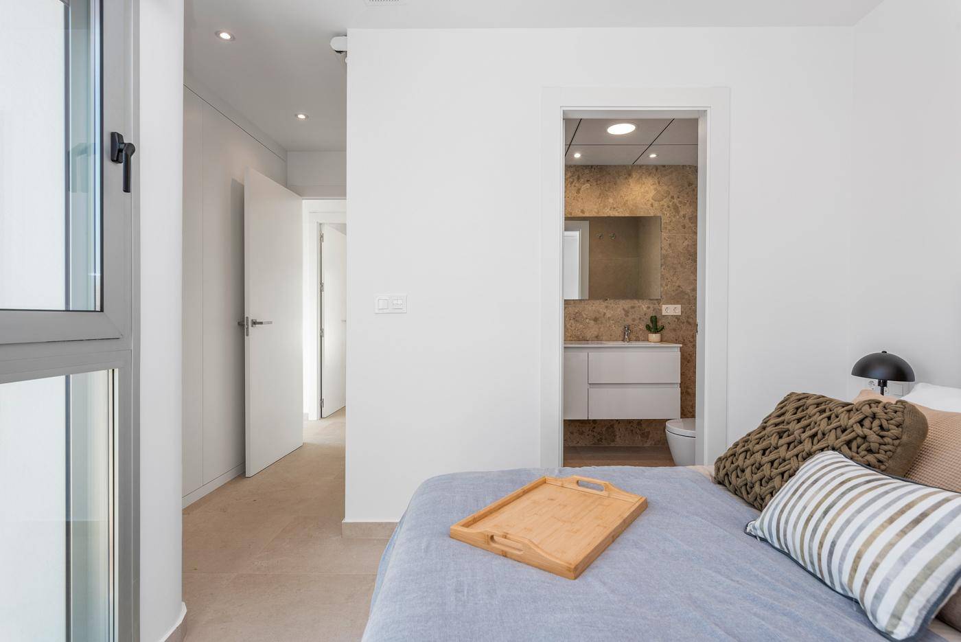 Schlafzimmer mit Zugang zu einem modernen Badezimmer und viel Tageslicht.